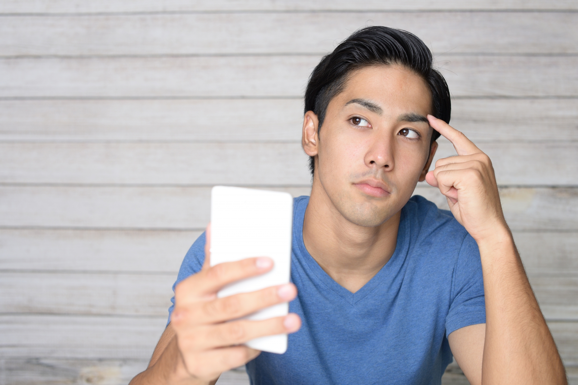 スマートフォンを持って考える男性