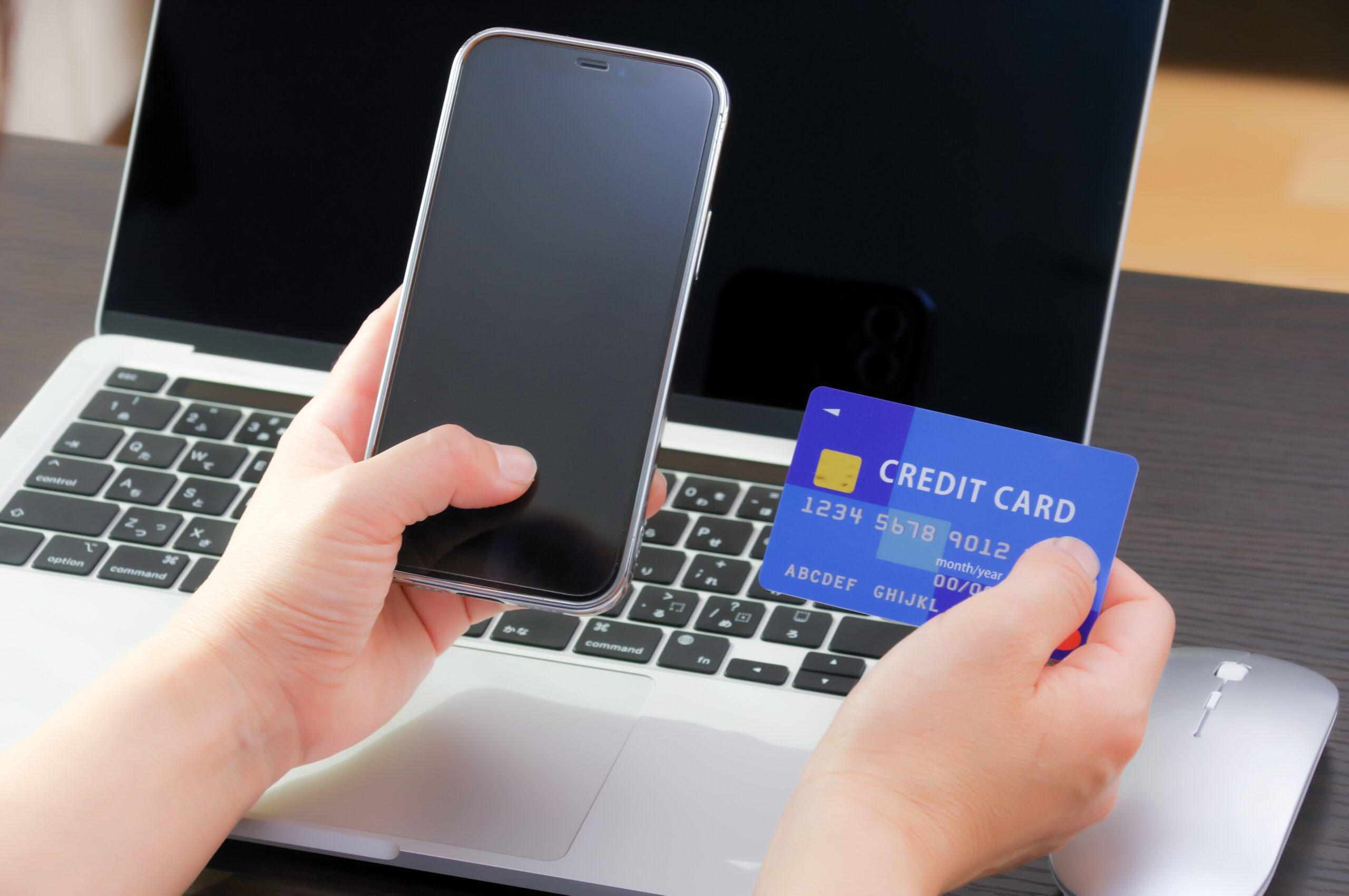 スマホとクレジットカードを持つ女性