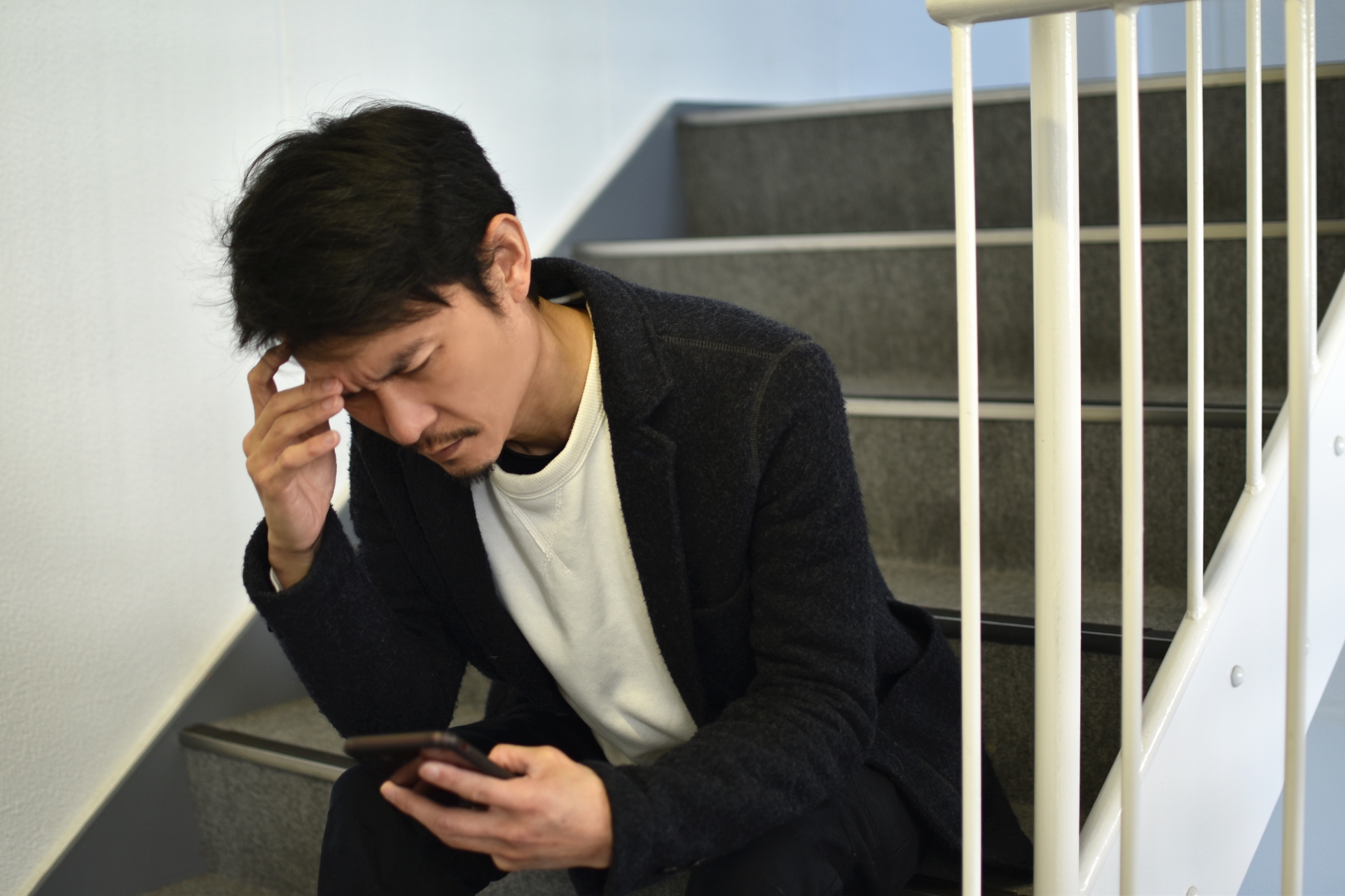 スマホを見て頭を抱える男