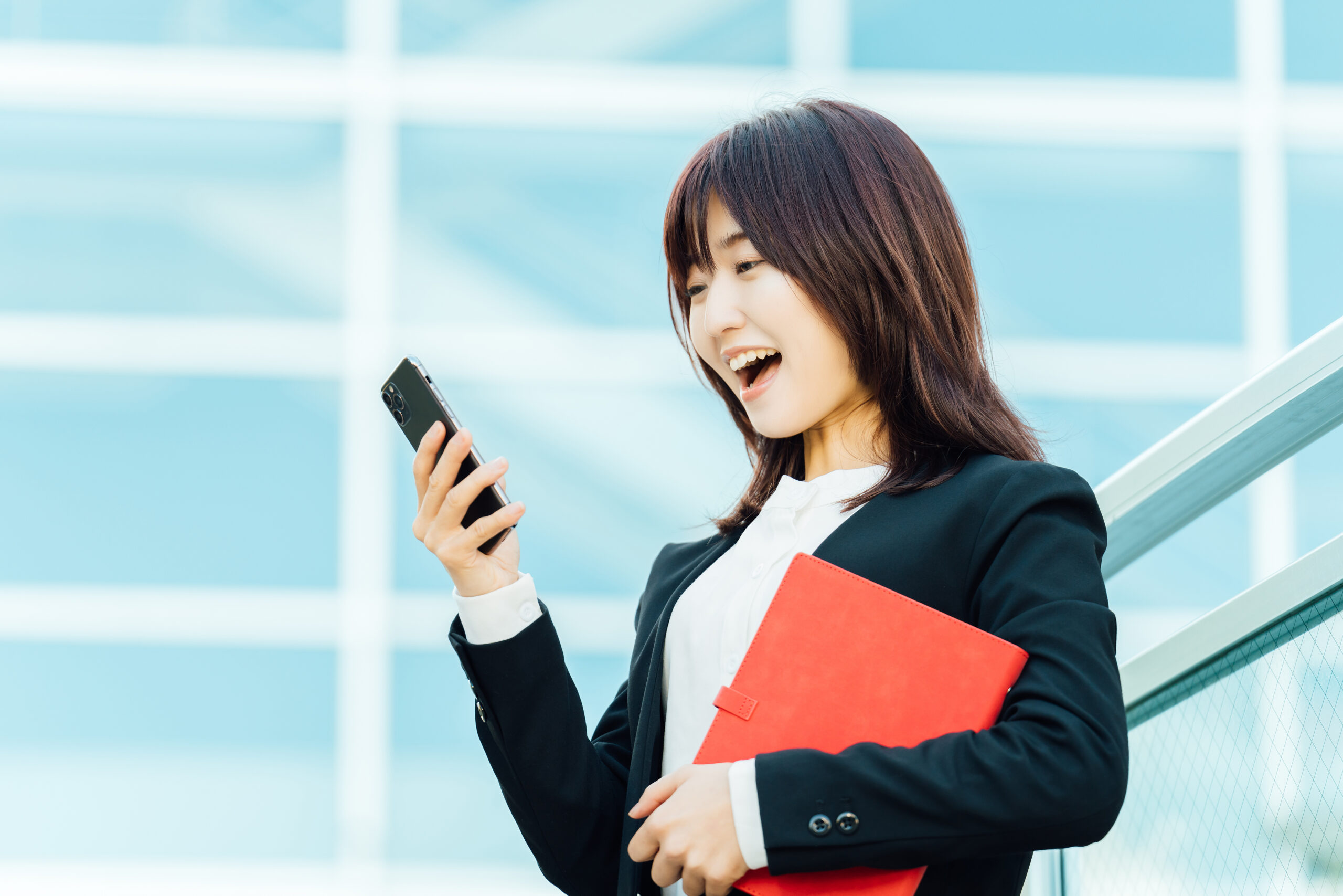 スマホの画面を見て喜ぶビジネスウーマン