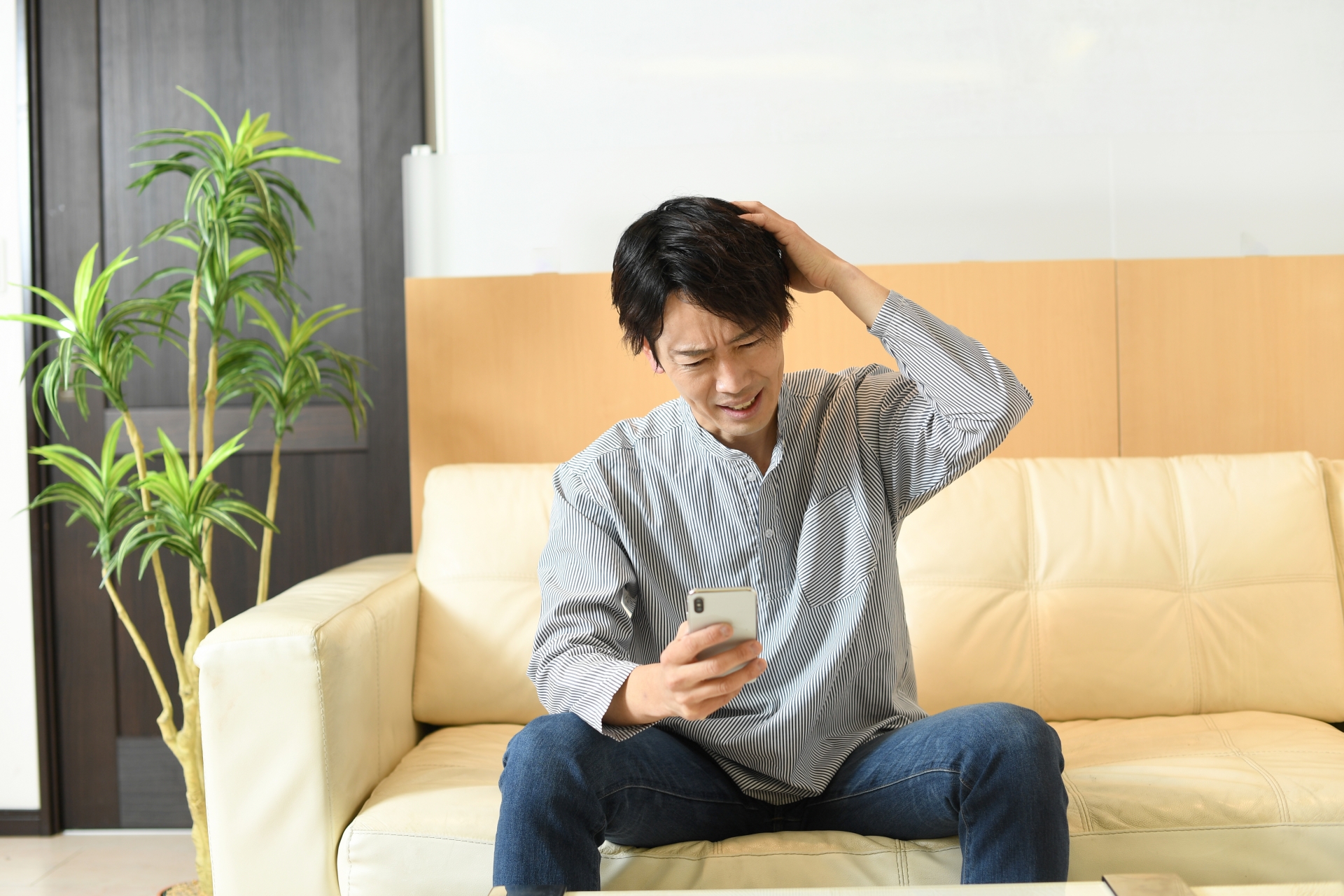 頭を抱えながらスマホを見る男性