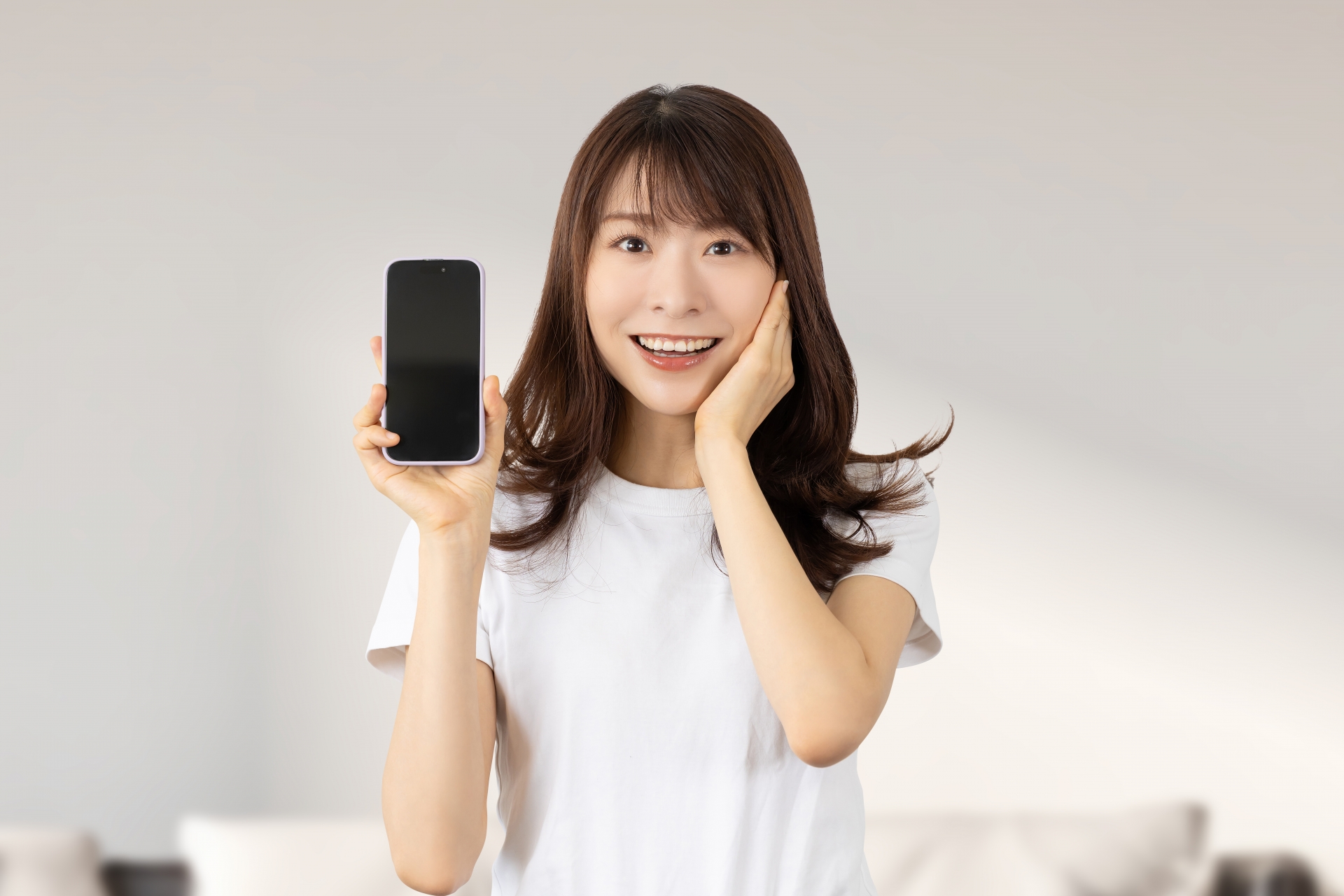 スマホを持って驚き喜ぶ笑顔の女性