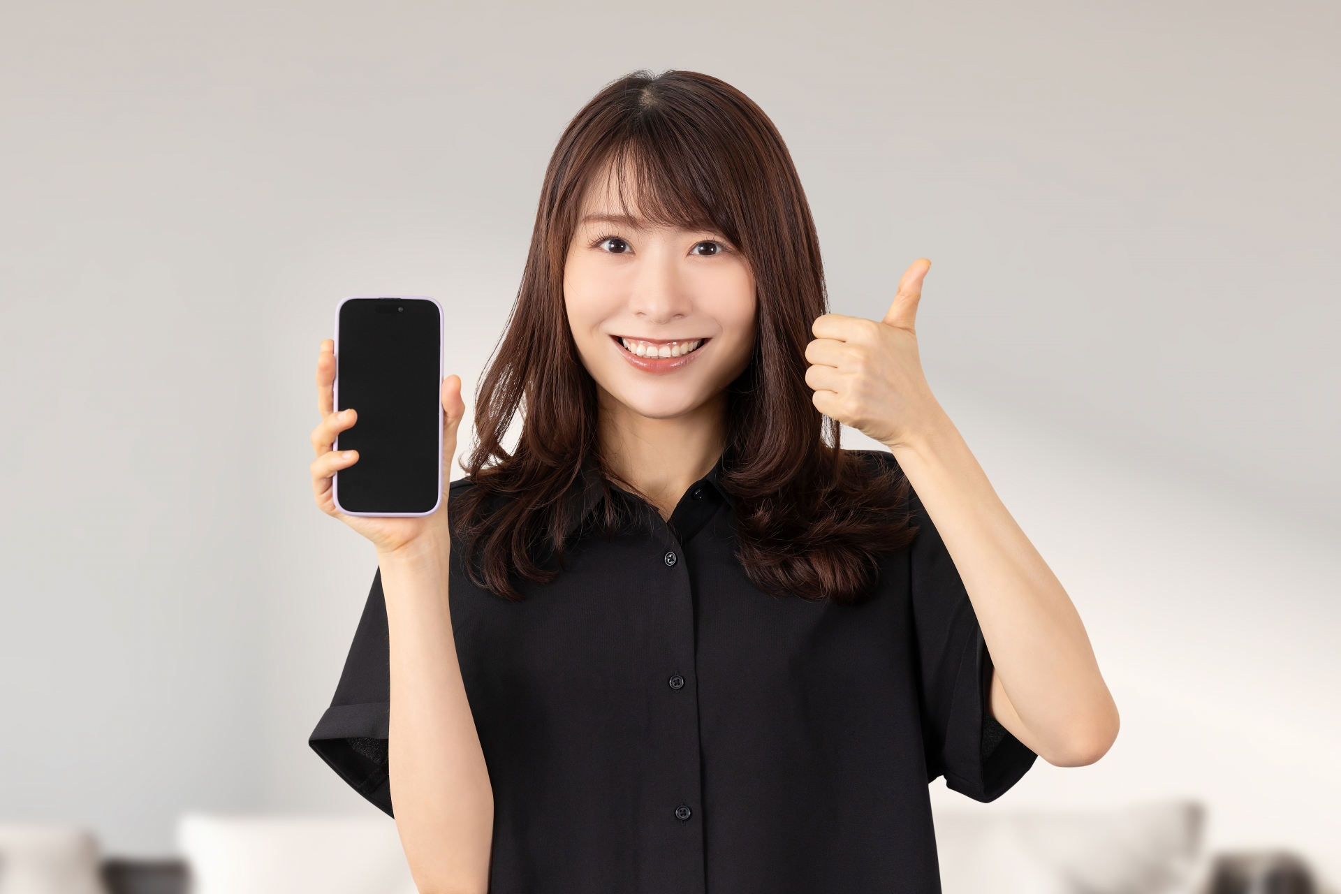 スマホを持っていいね！のポーズをする女性