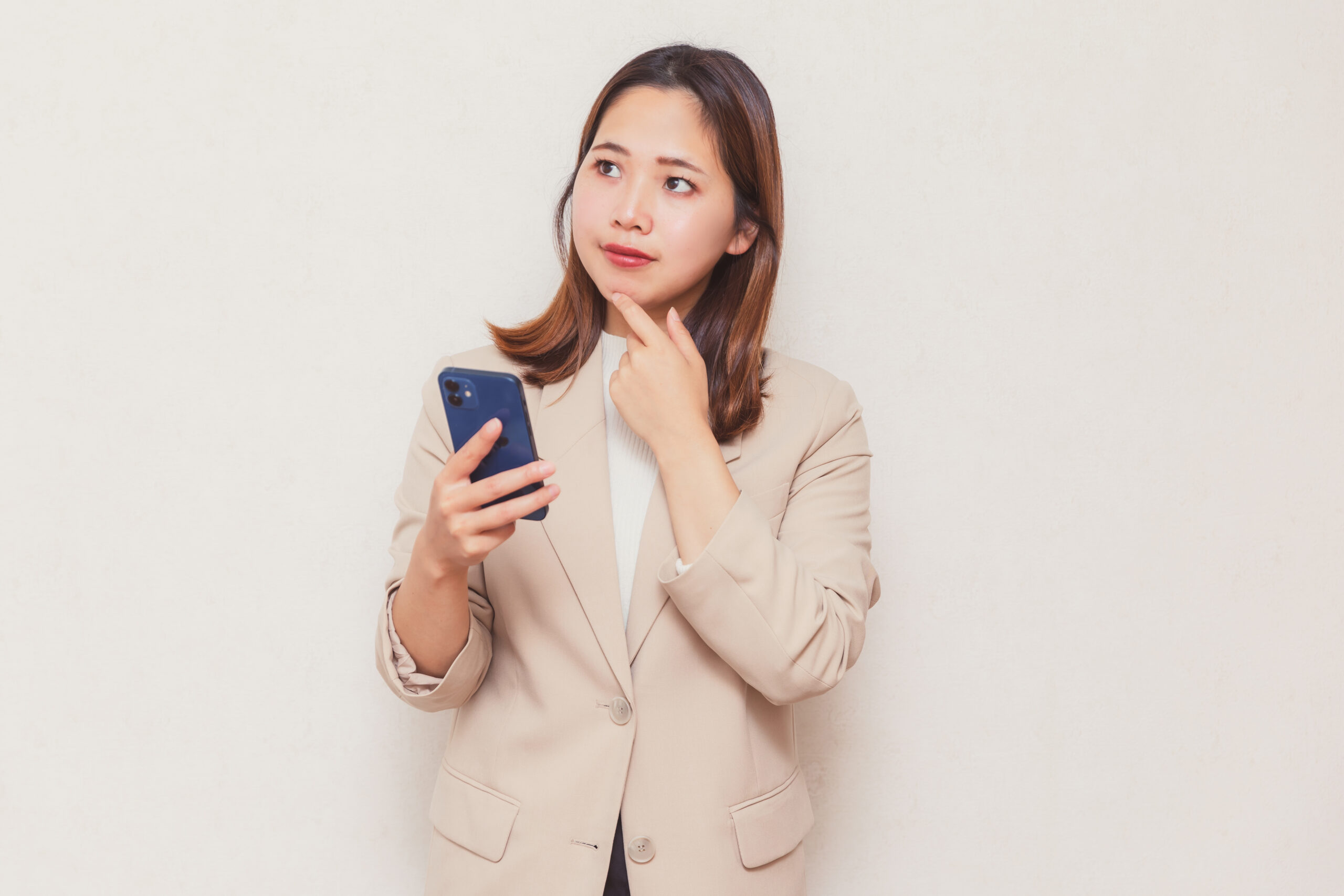 スマホを持って悩むビジネスウーマン