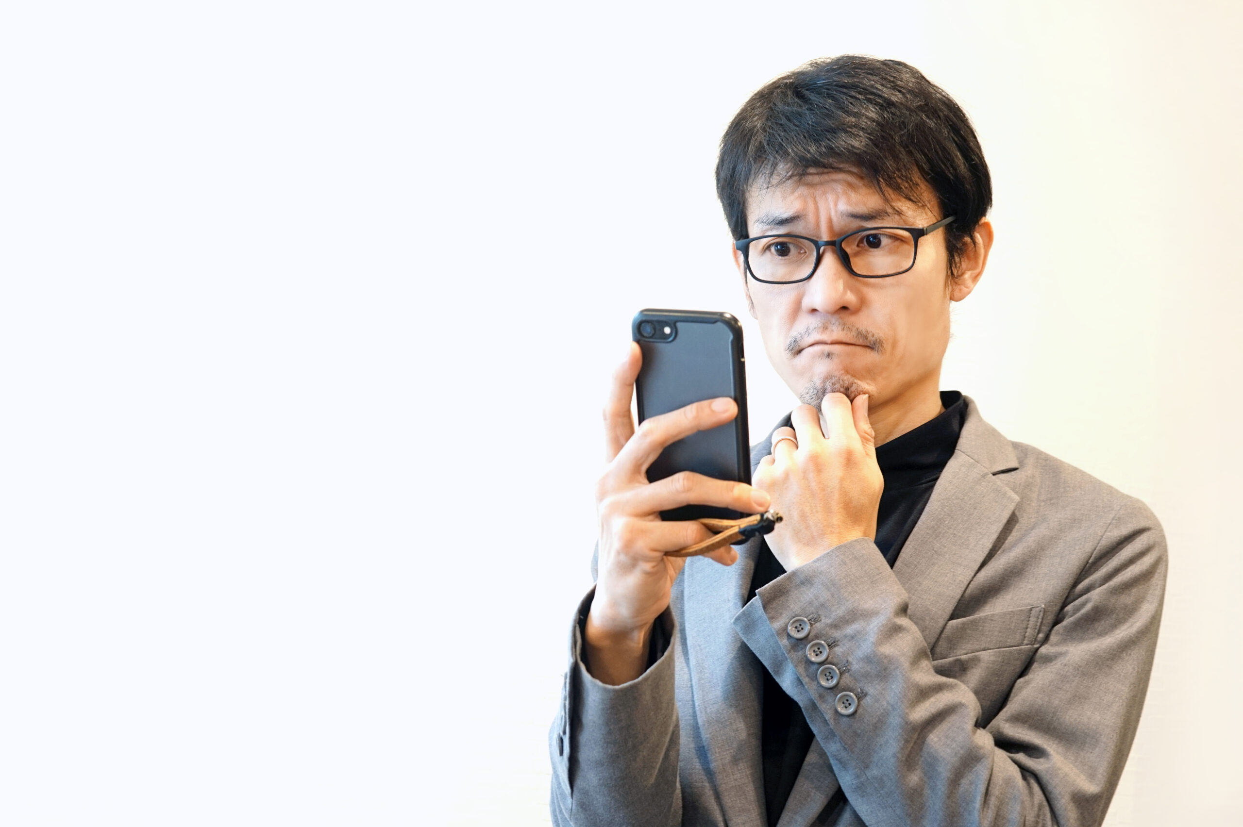 スマホを見て悩むビジネスマン