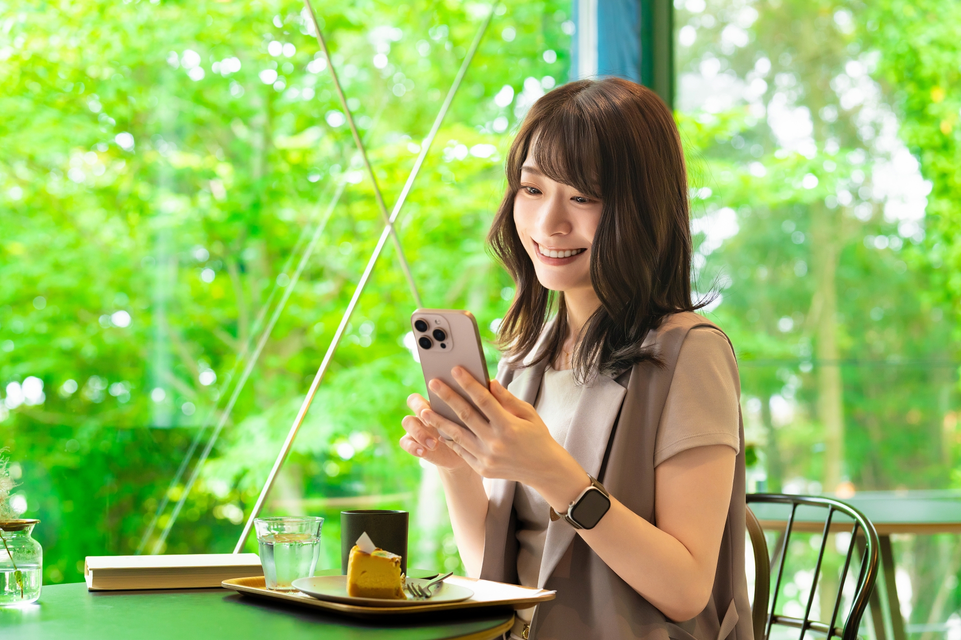 カフェでスマホを使う笑顔の女性