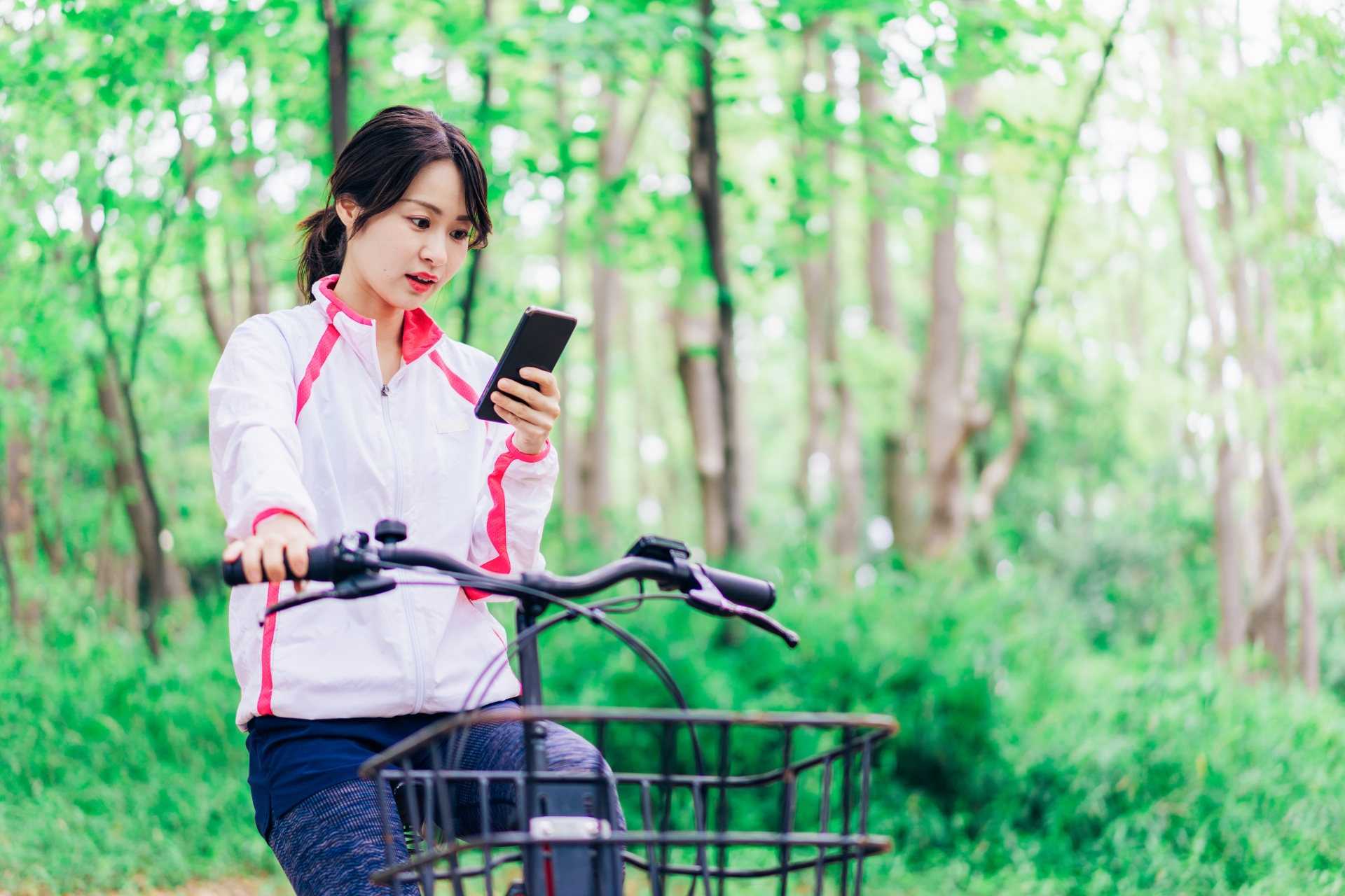 自転車に乗りながらスマホを使う女性