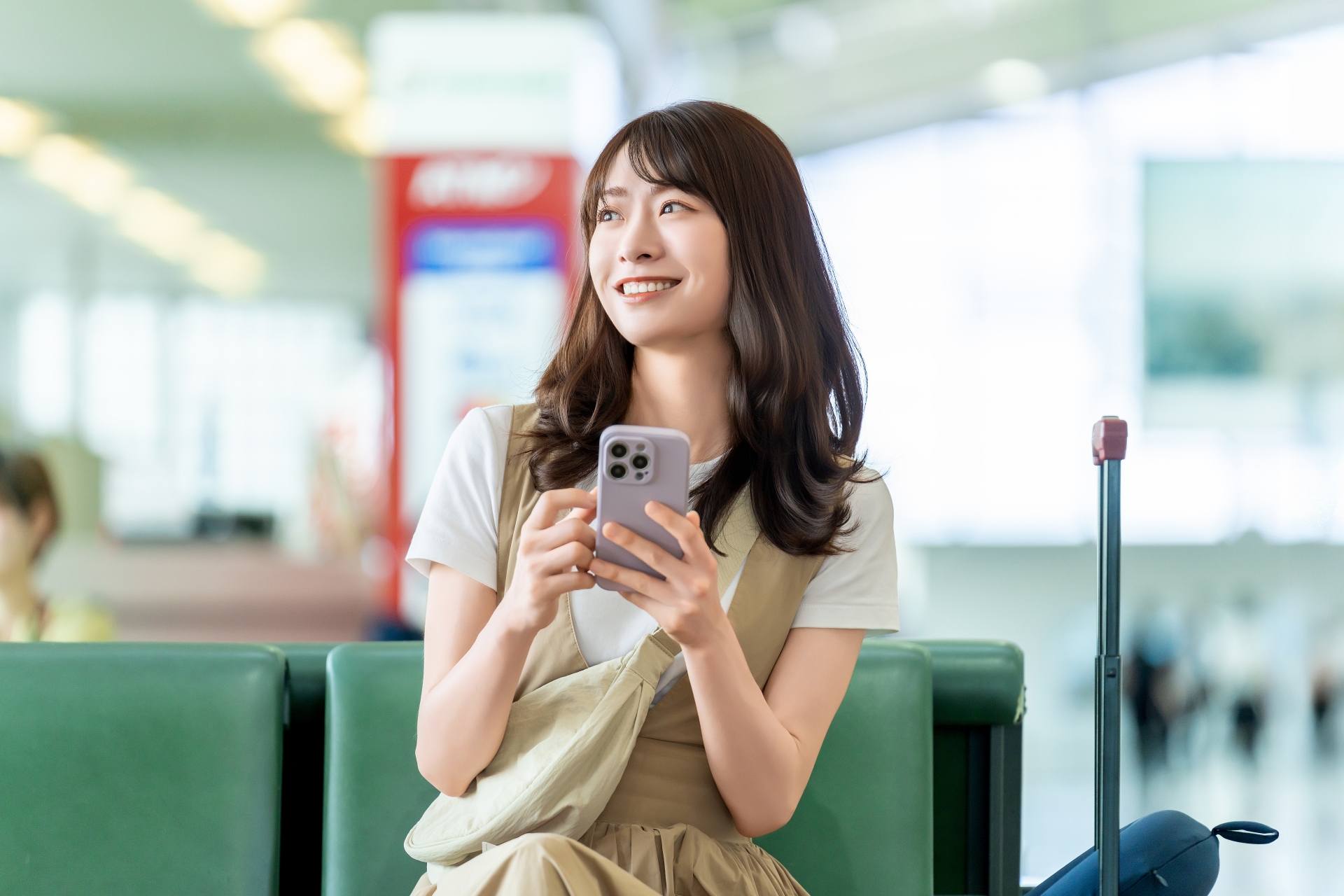 空港でスマホを使う旅行中の女性