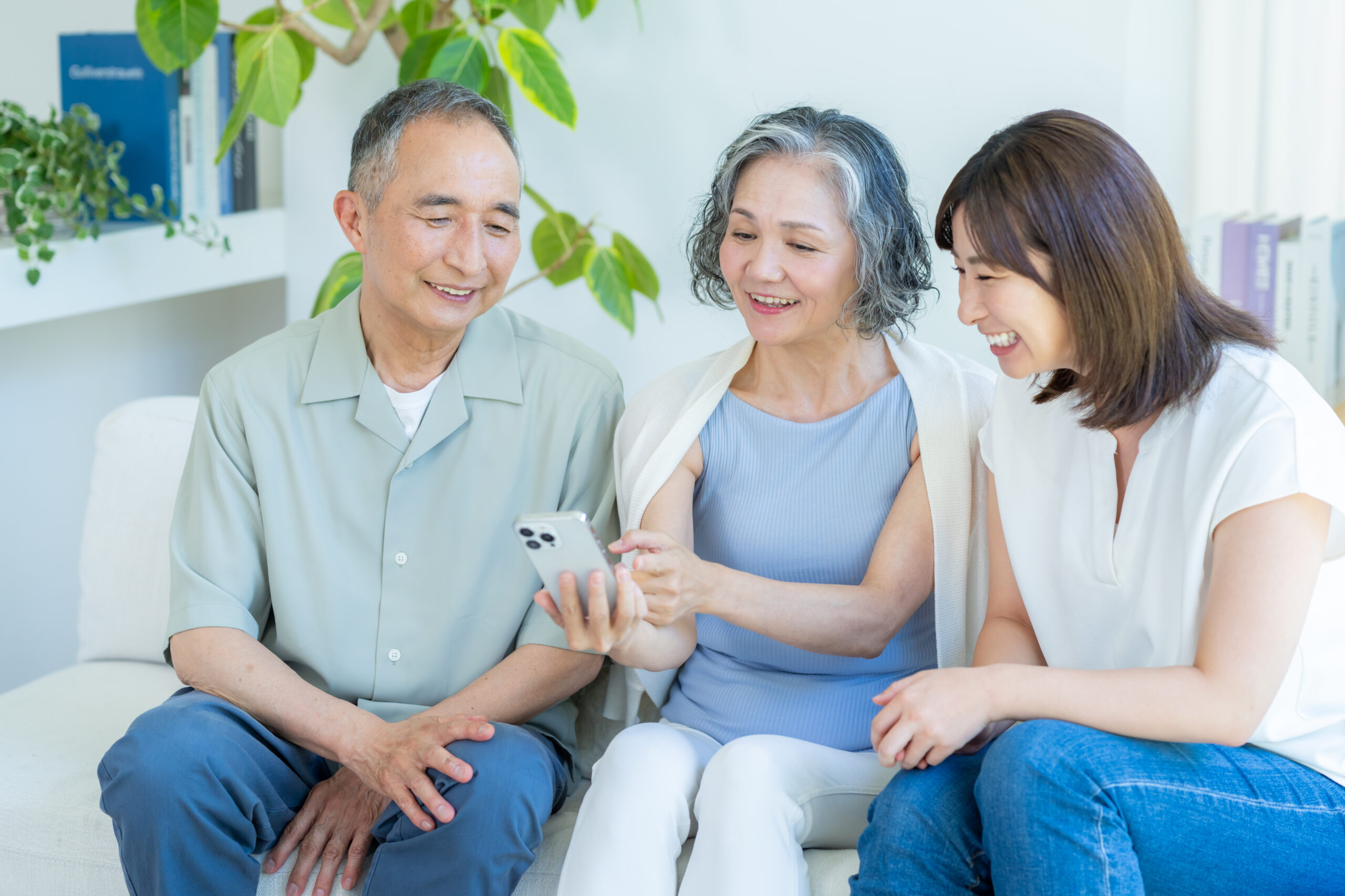 リビングでスマホを見るシニア夫婦と子供