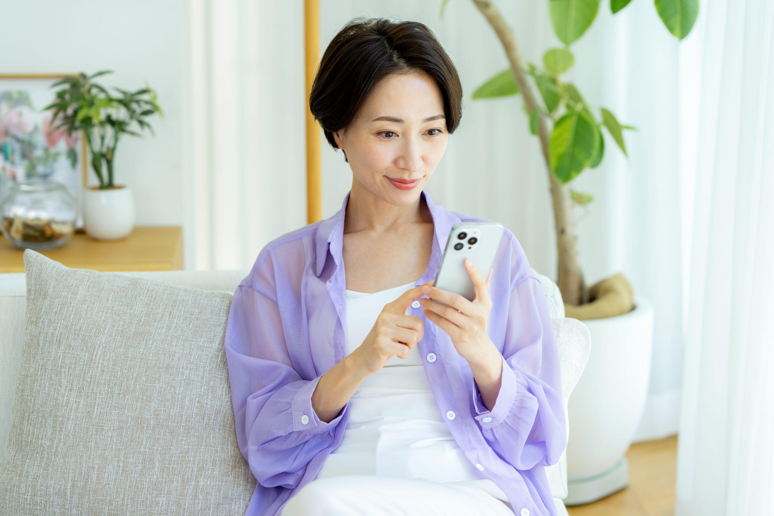 部屋でスマホを使うミドル女性