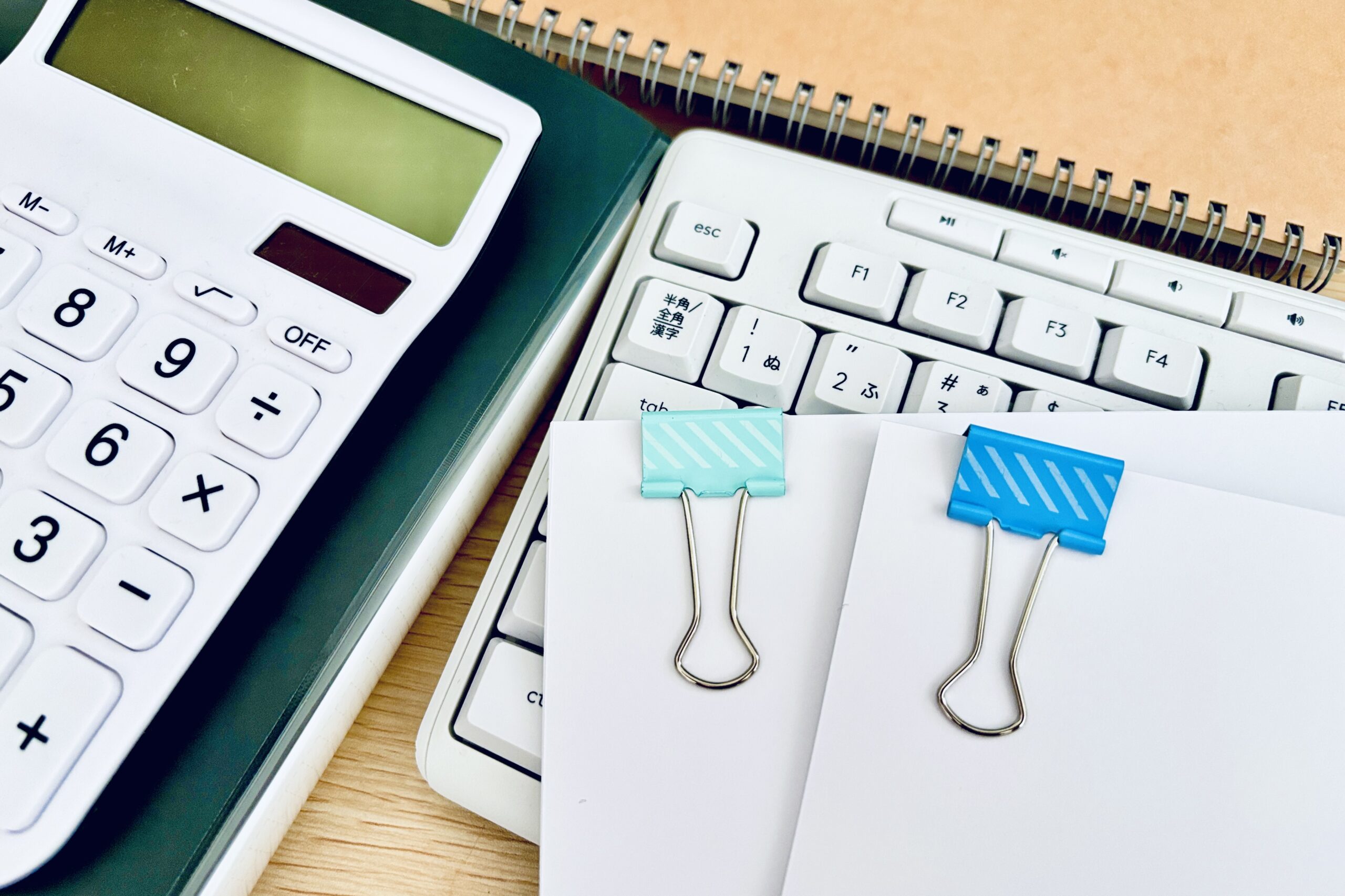 クリップで挟んだ資料とPCと電卓