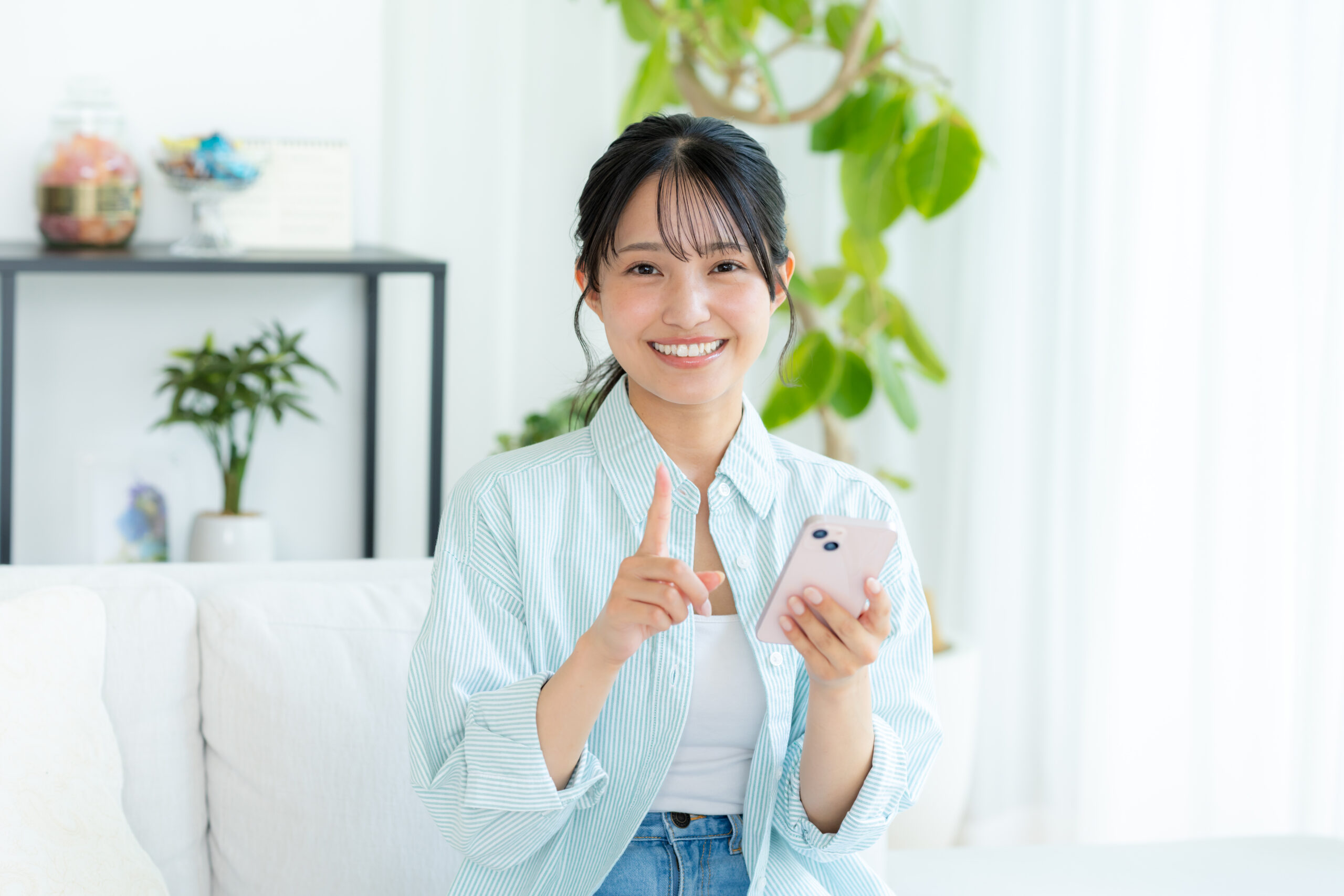 部屋でスマホを操作する若い女性