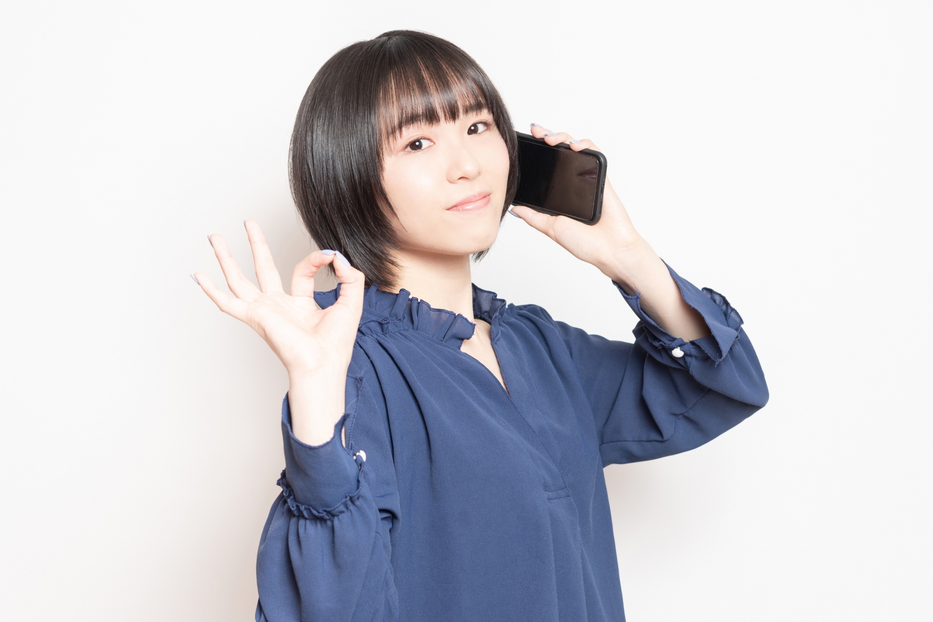 スマホを持ってOKサインをする人