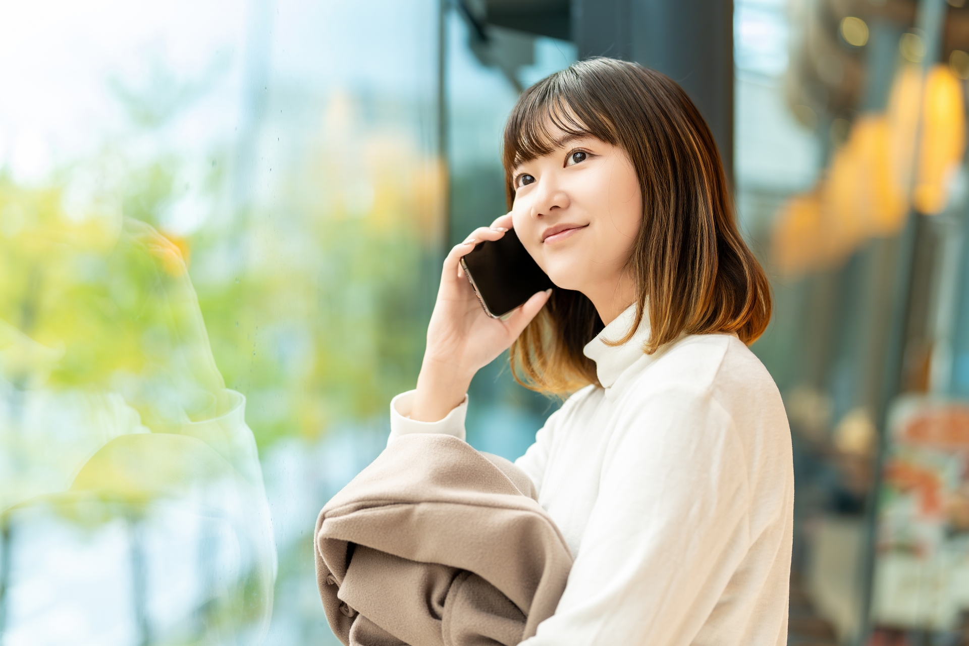 窓の外を見ながらスマホで話す女性