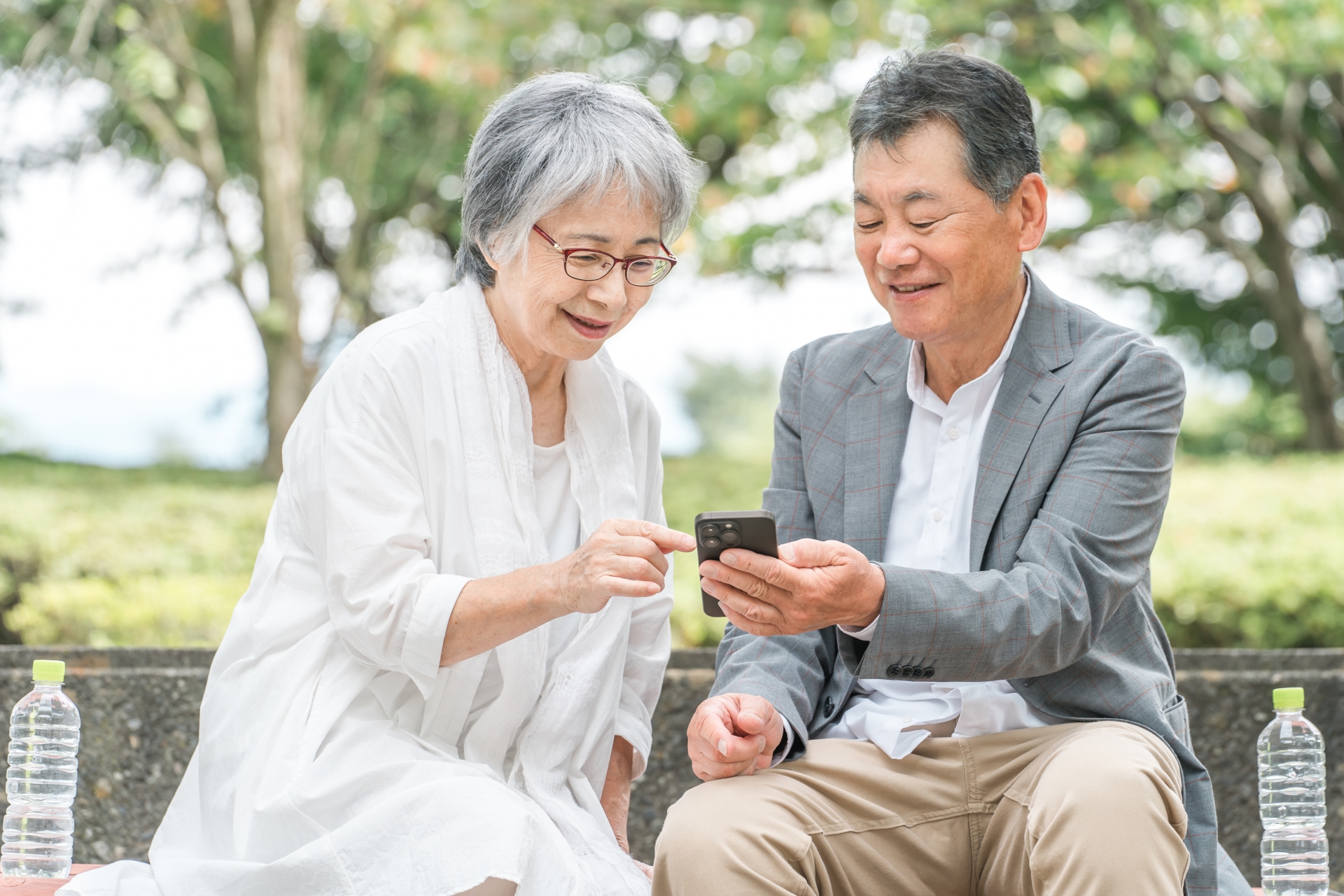 公園でスマホを見ながら会話する高齢者夫婦