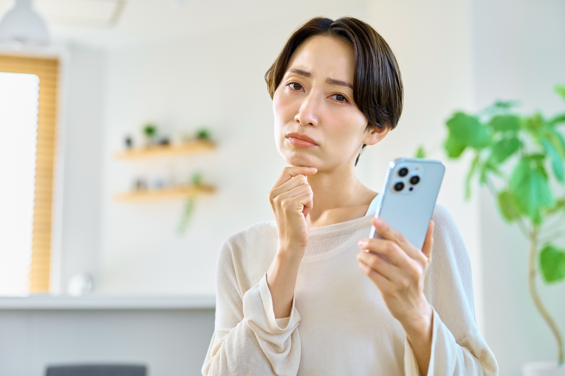 携帯を持って考える女性