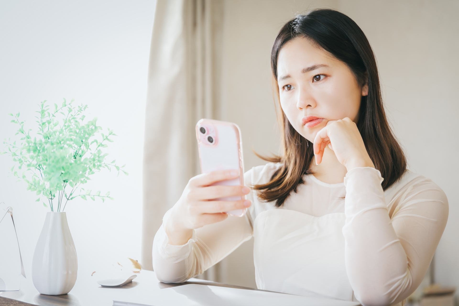 スマホを持って悩む女性