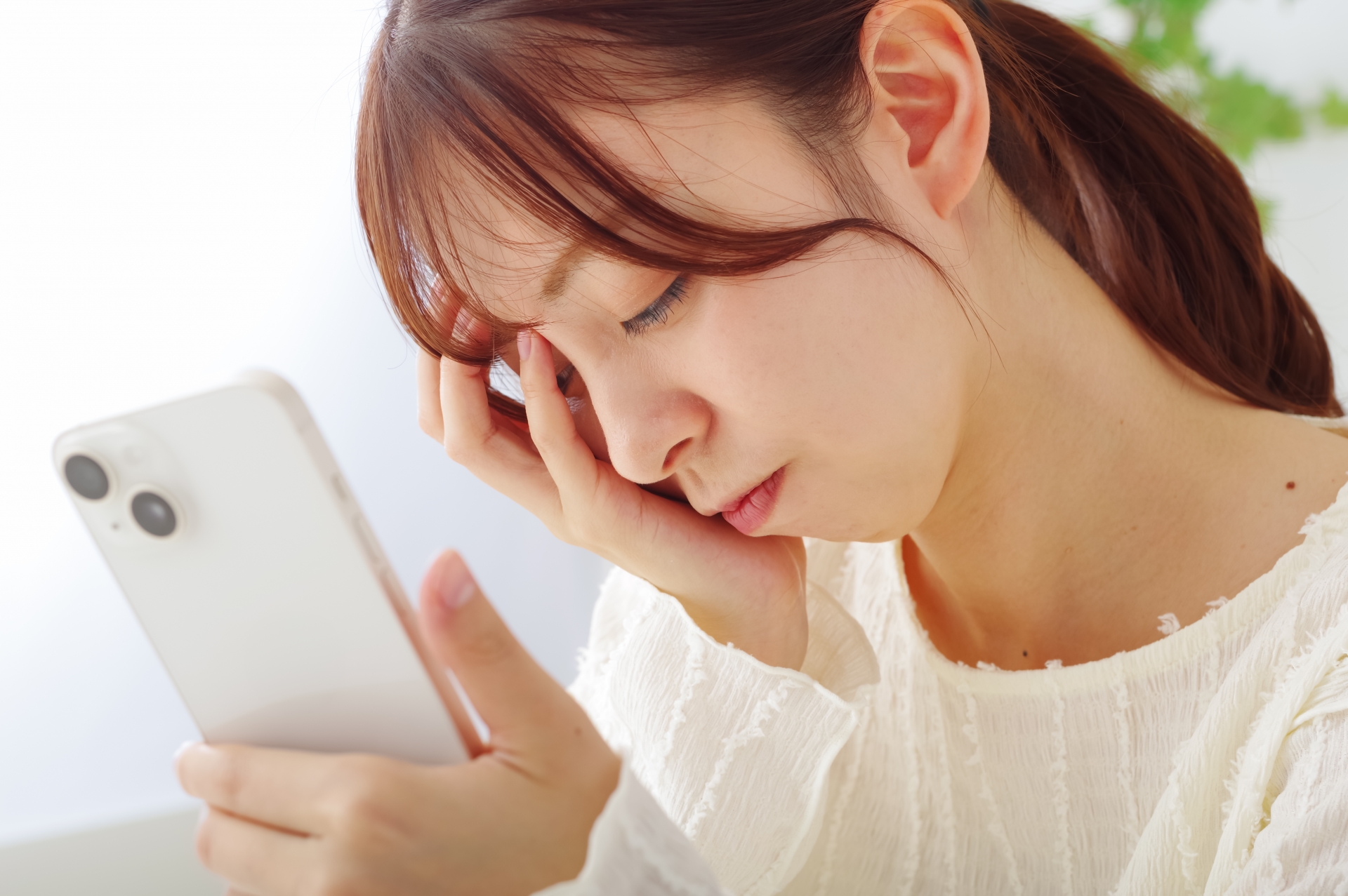 スマホを見て冴えない表情をする女性