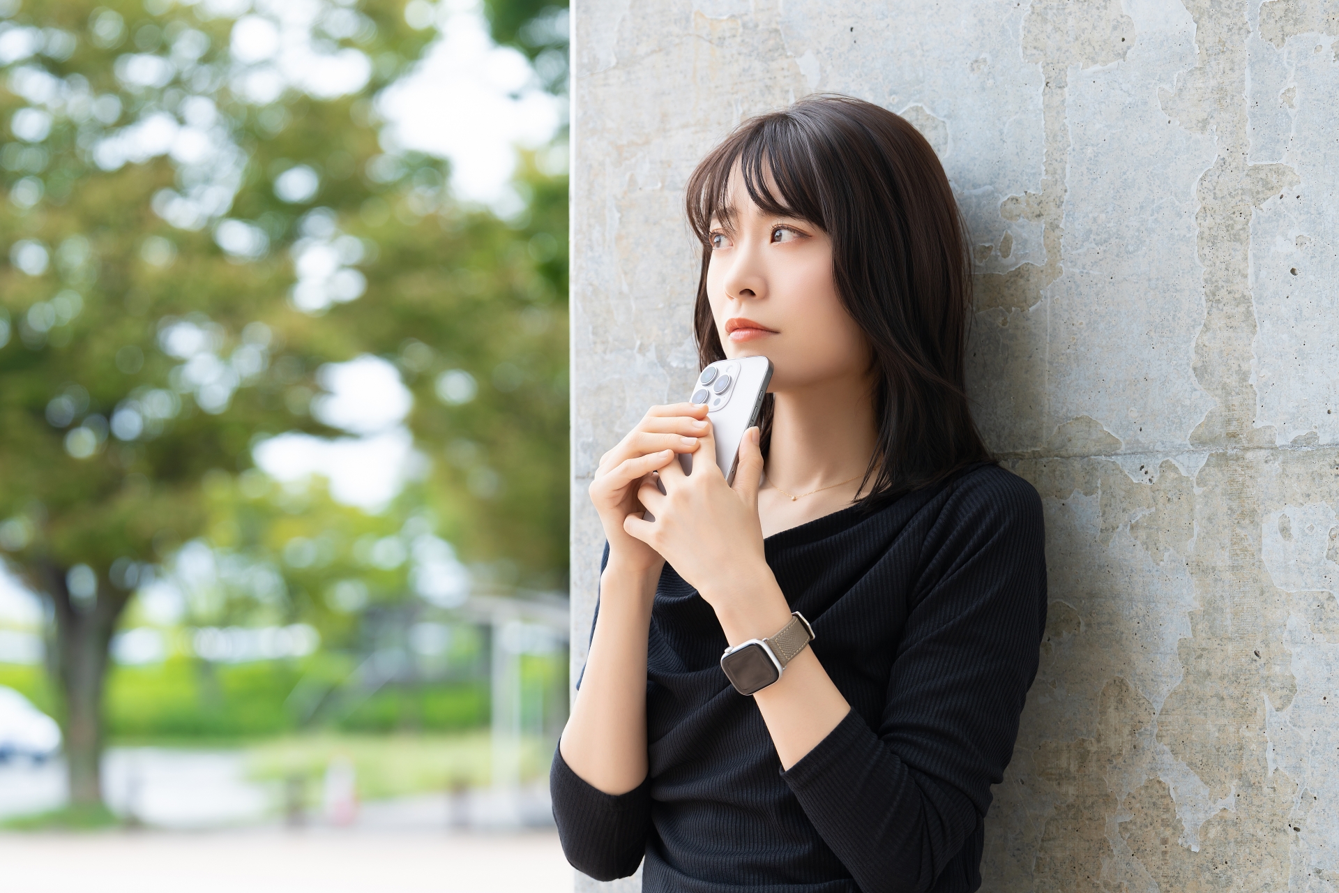 スマホを持って考えごとをする女性