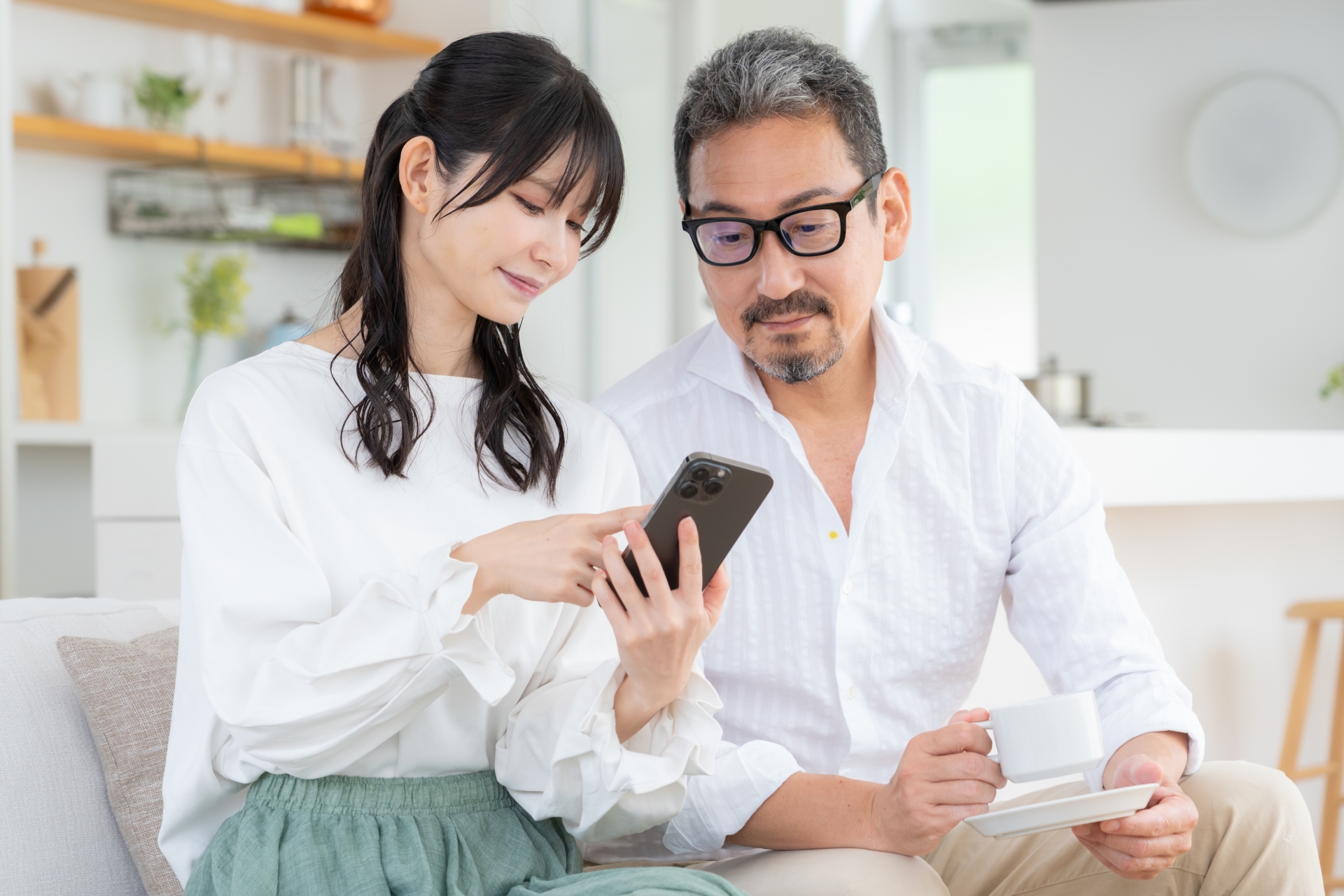 リビングでスマホを見るミドルの夫婦