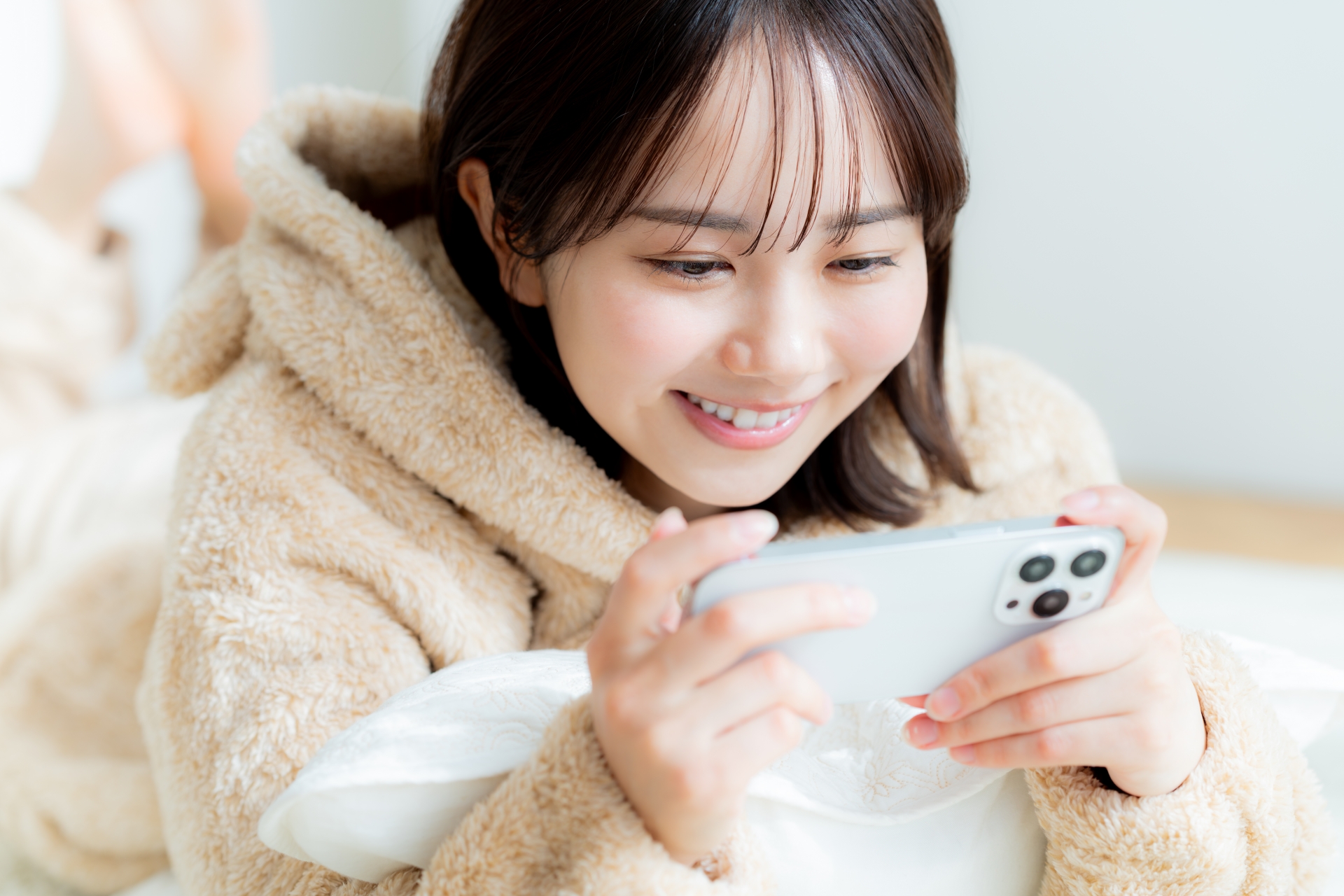 部屋でスマホを操作する若い女性