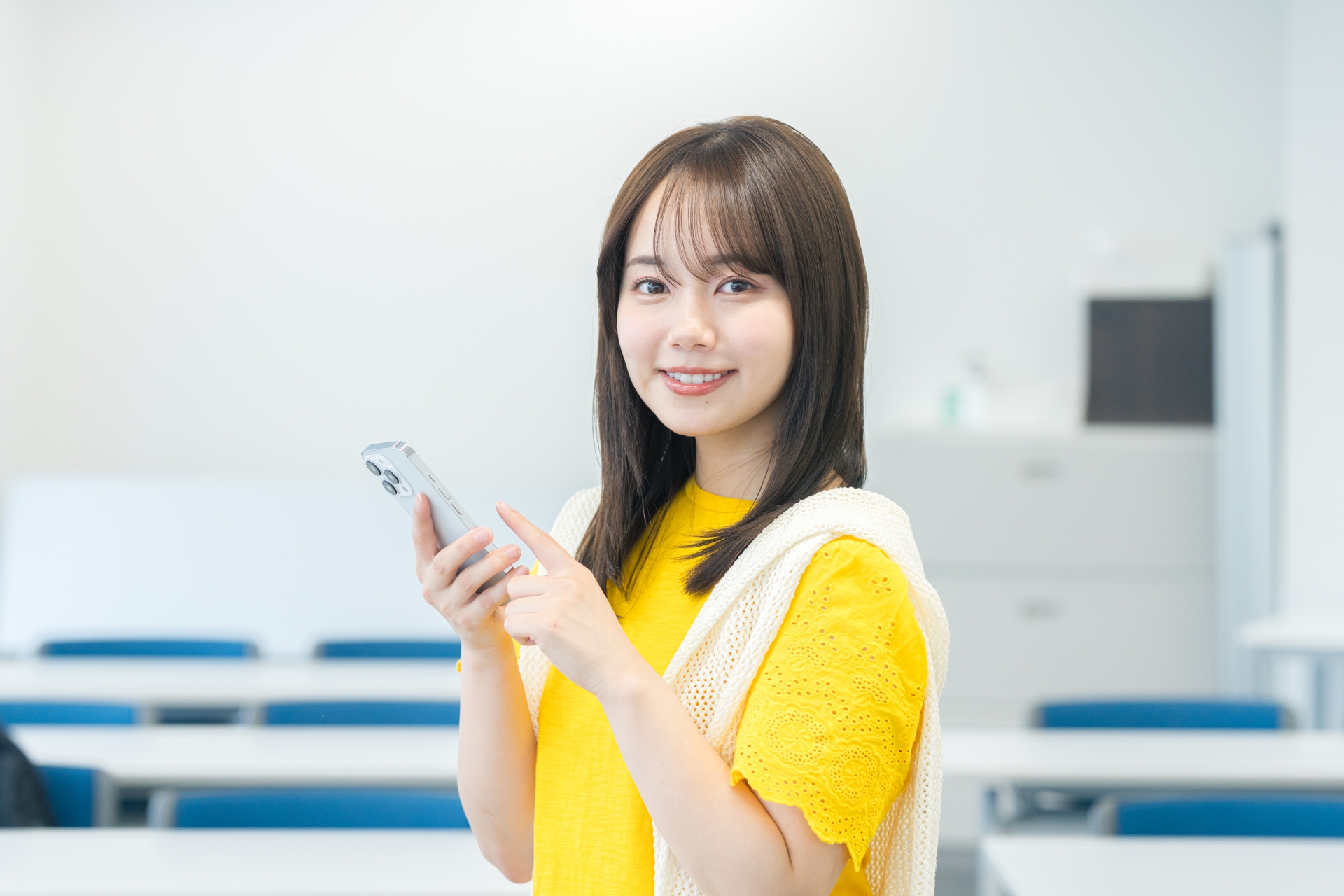 教室でスマホを見る女子大学生