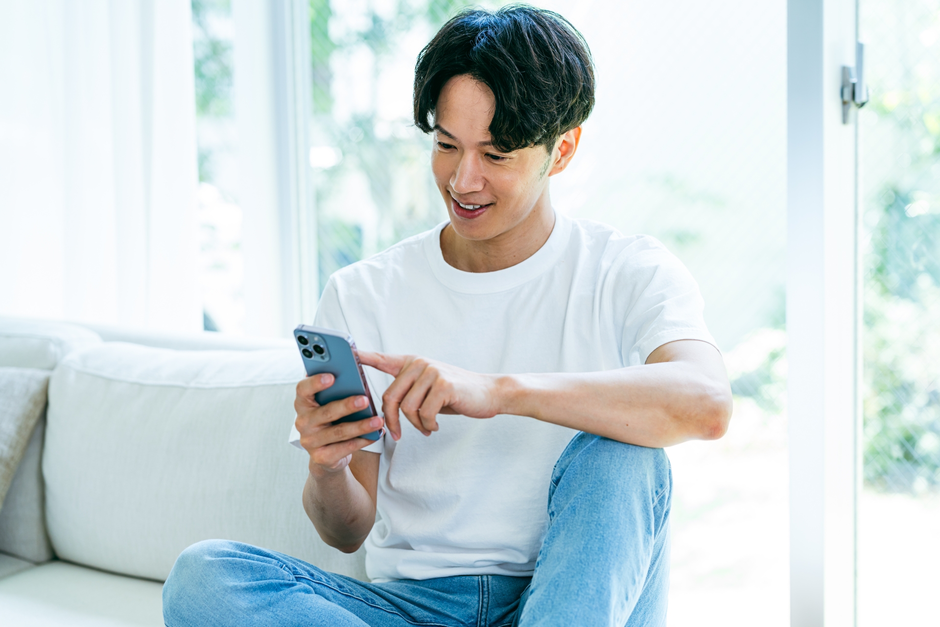 ソファでスマホを操作する男性