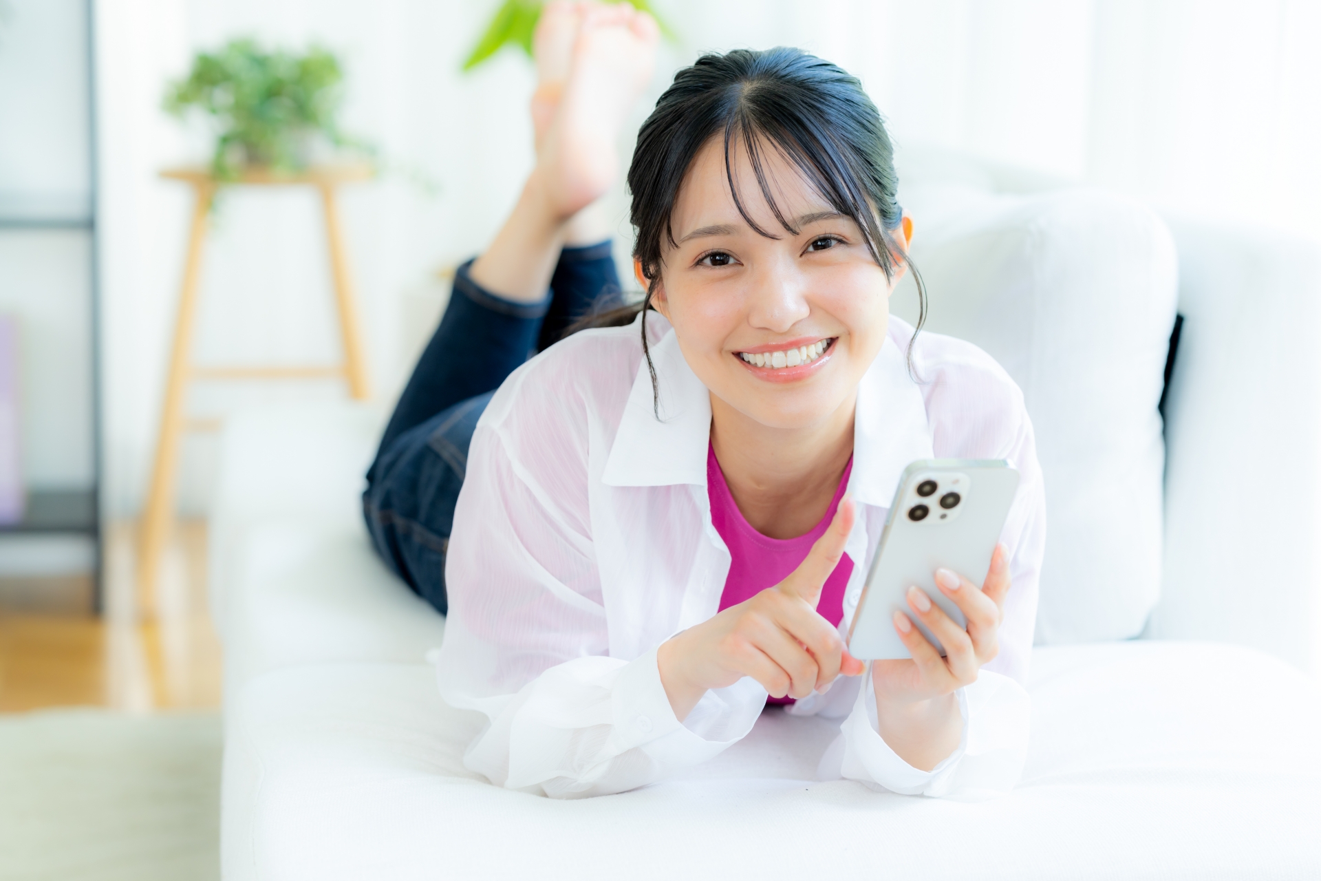 部屋でスマホを操作する女性