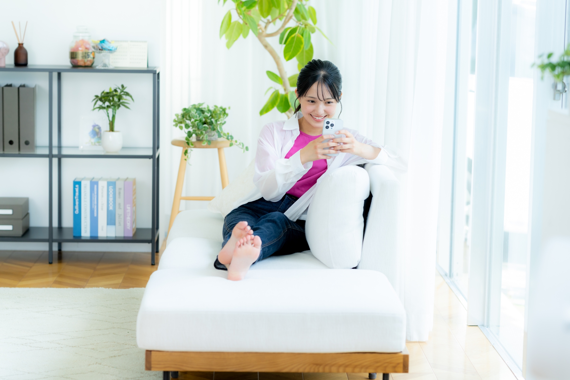 部屋でスマホを操作する若い女性