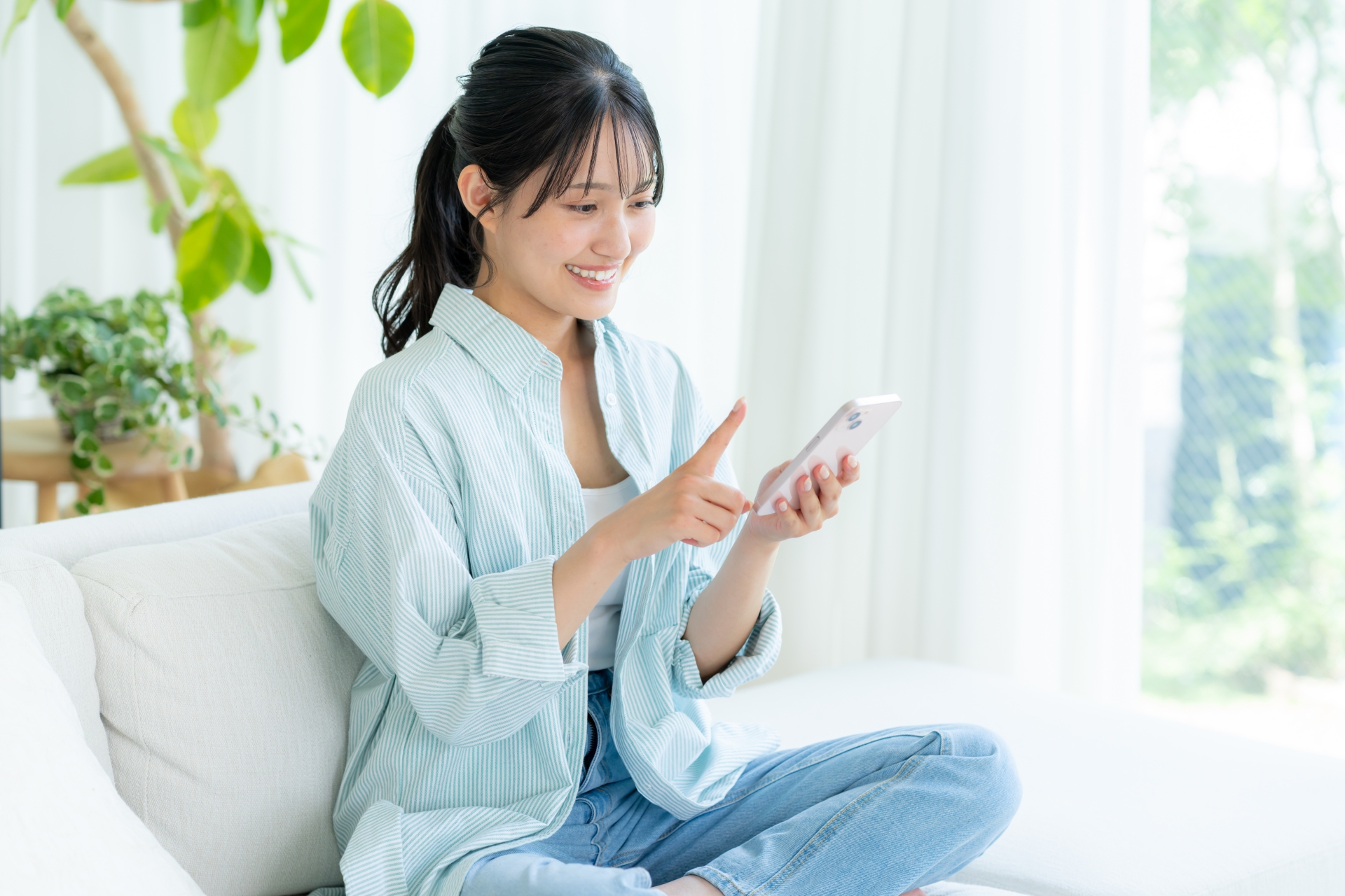 部屋でスマホを操作する女性