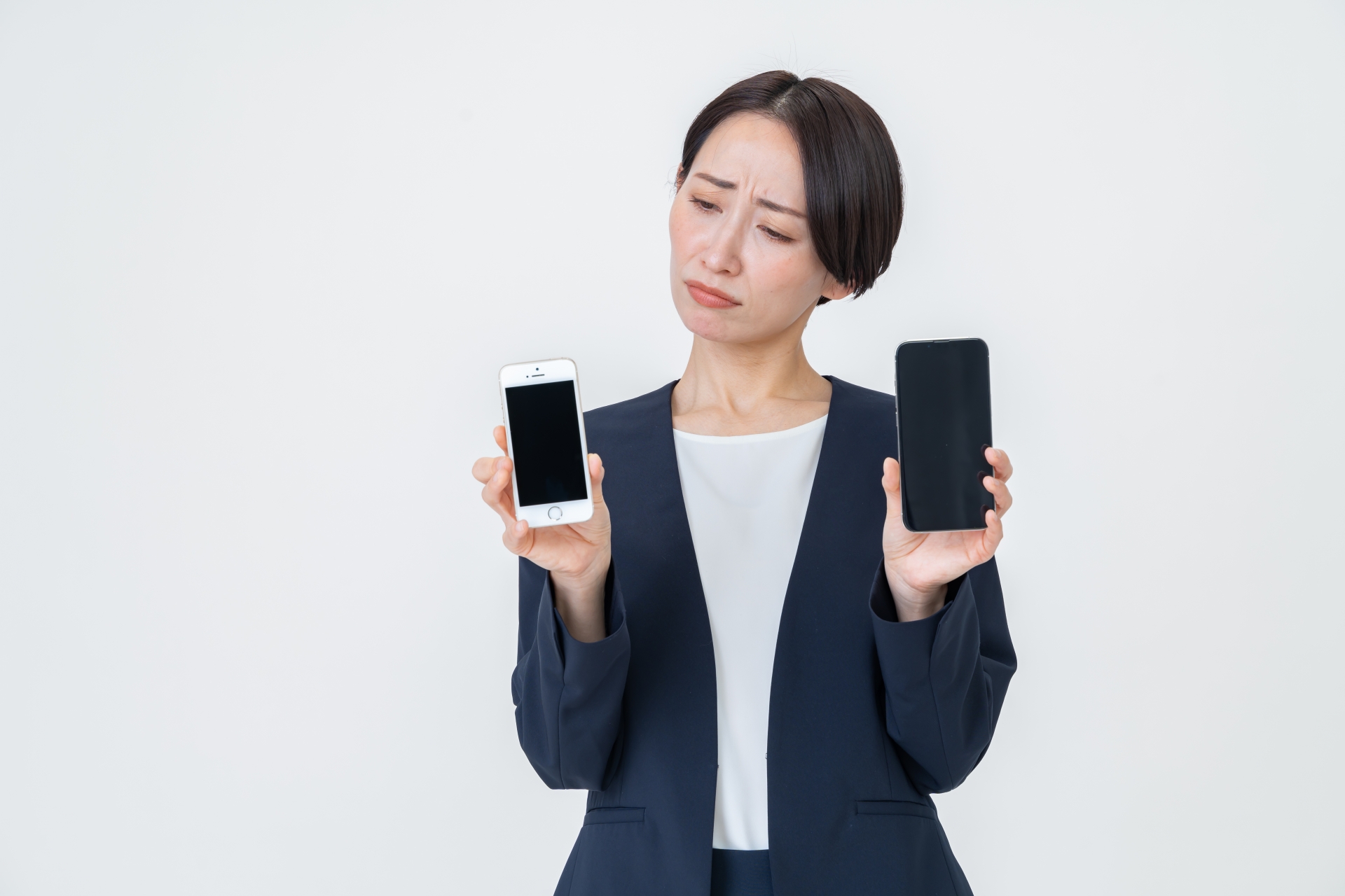 2台のスマホを持って悩む女性