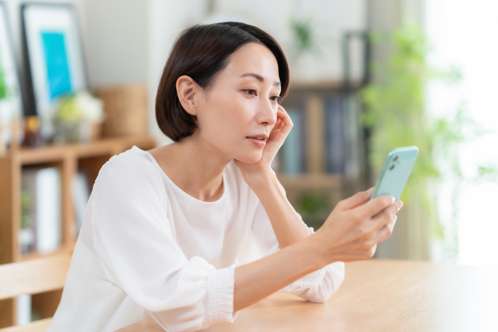 スマホを見ながら頬杖をつく女性