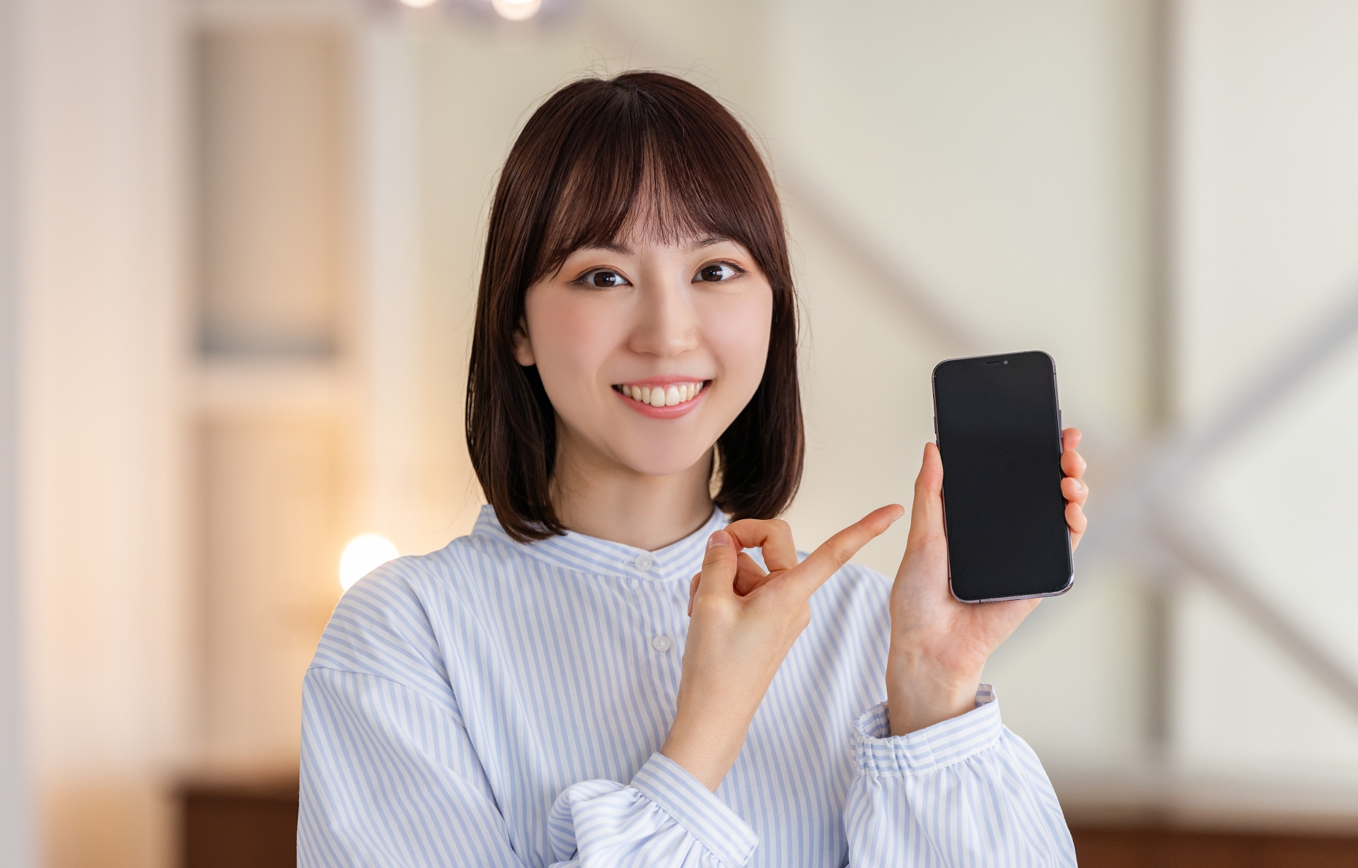 スマホを指差す笑顔のビジネスウーマン