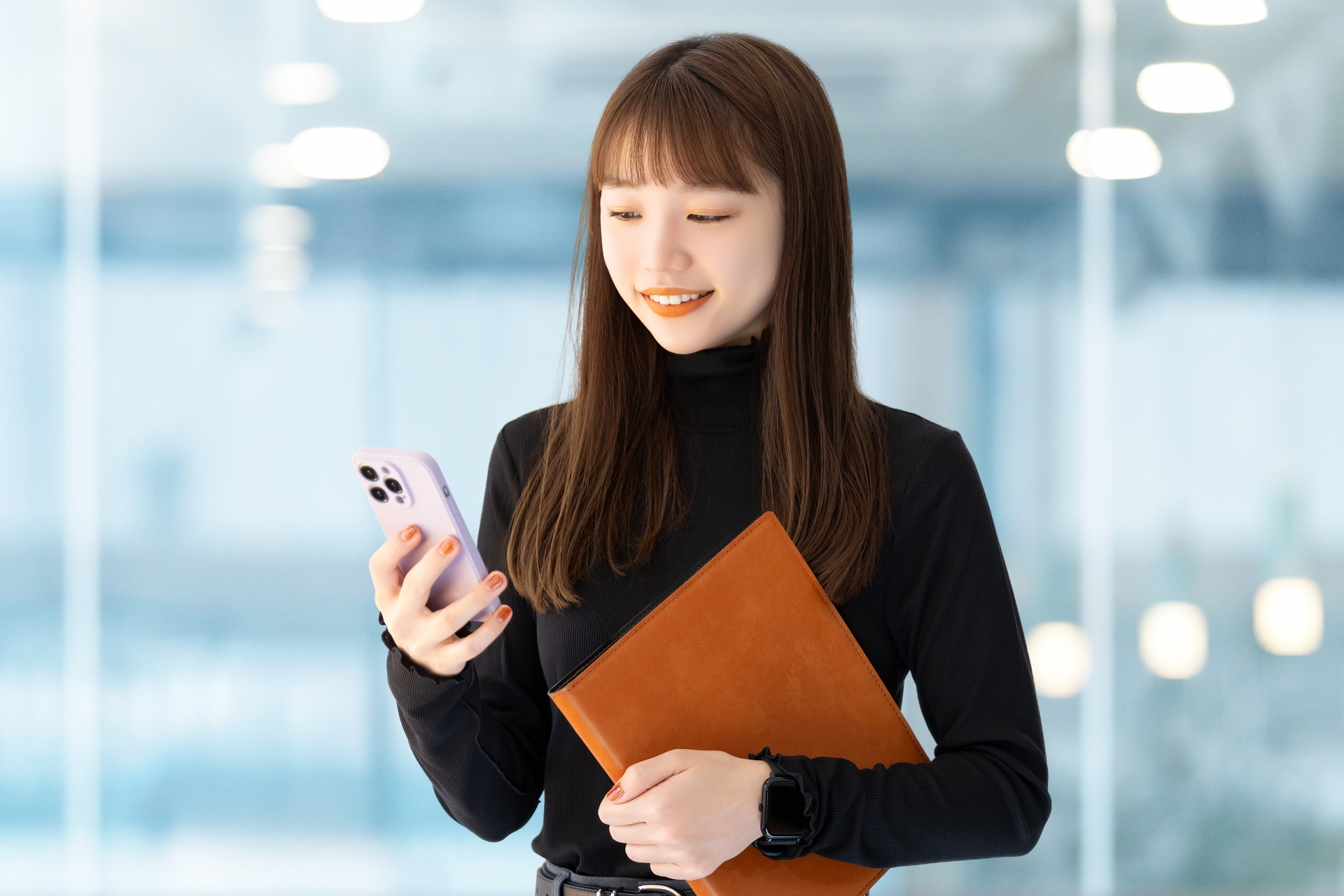 スマホとバインダーを持つ笑顔の女性