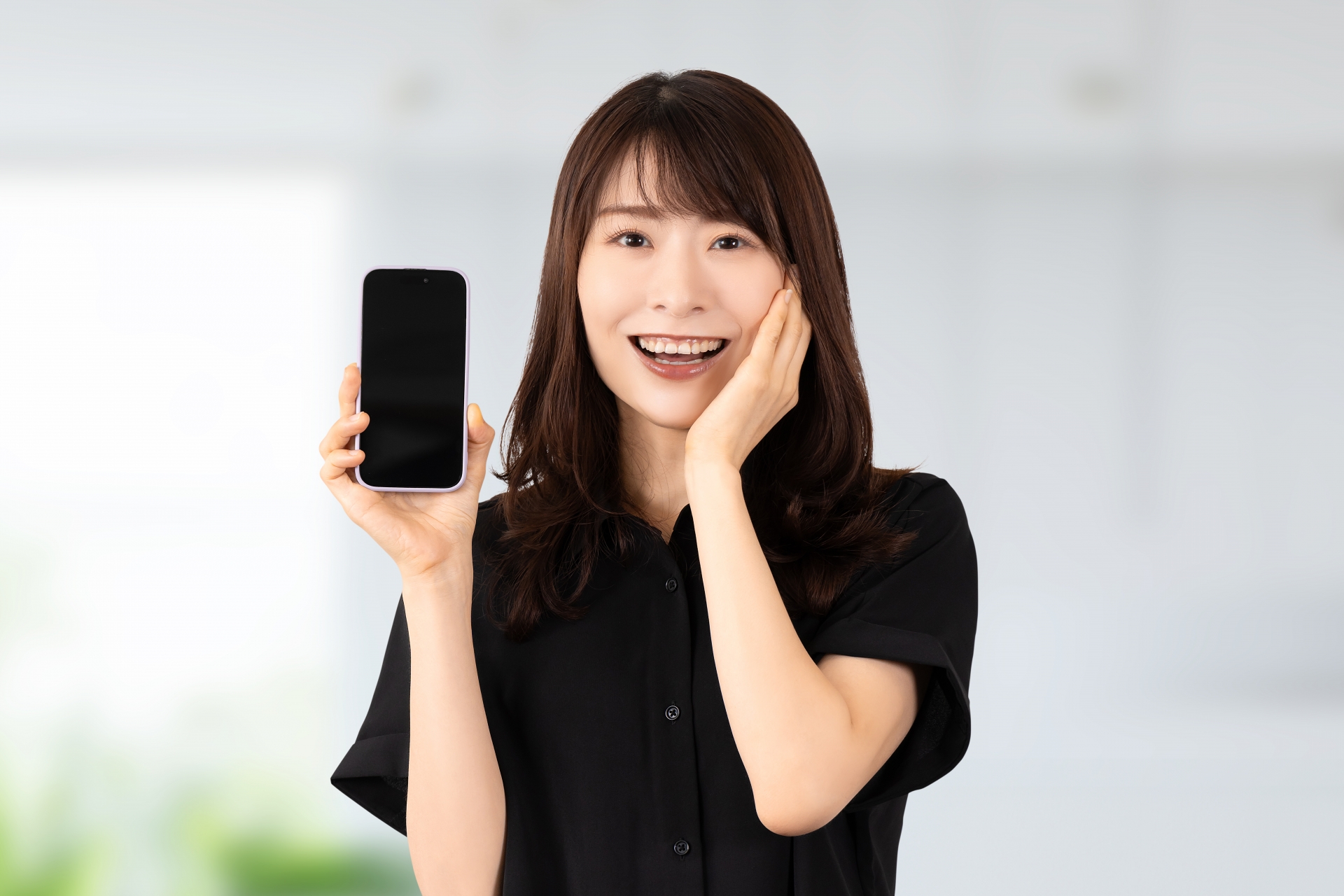 スマホを持って驚き喜ぶ笑顔の女性