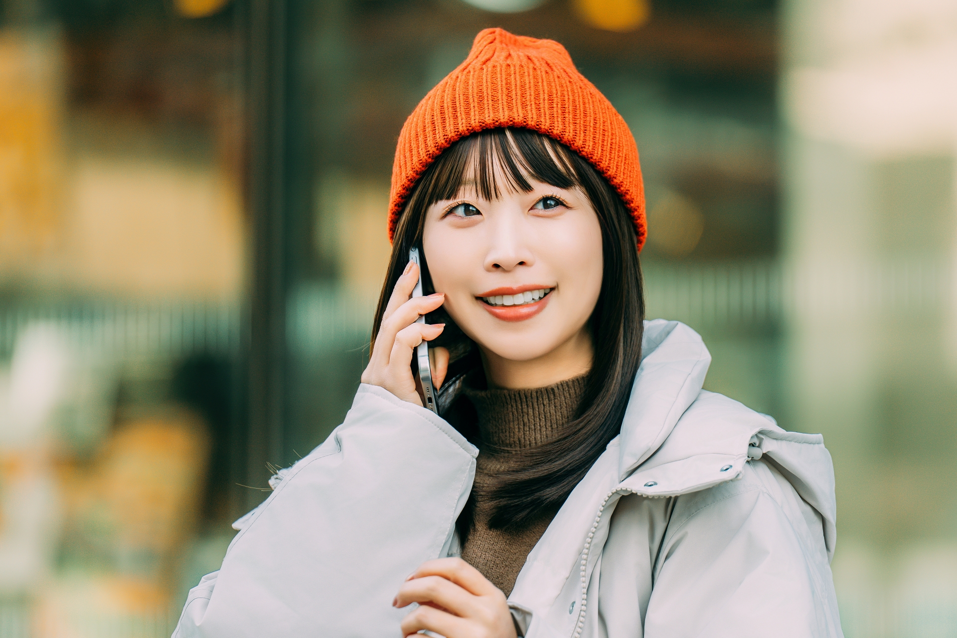 冬の街角でスマホを使う笑顔の女性