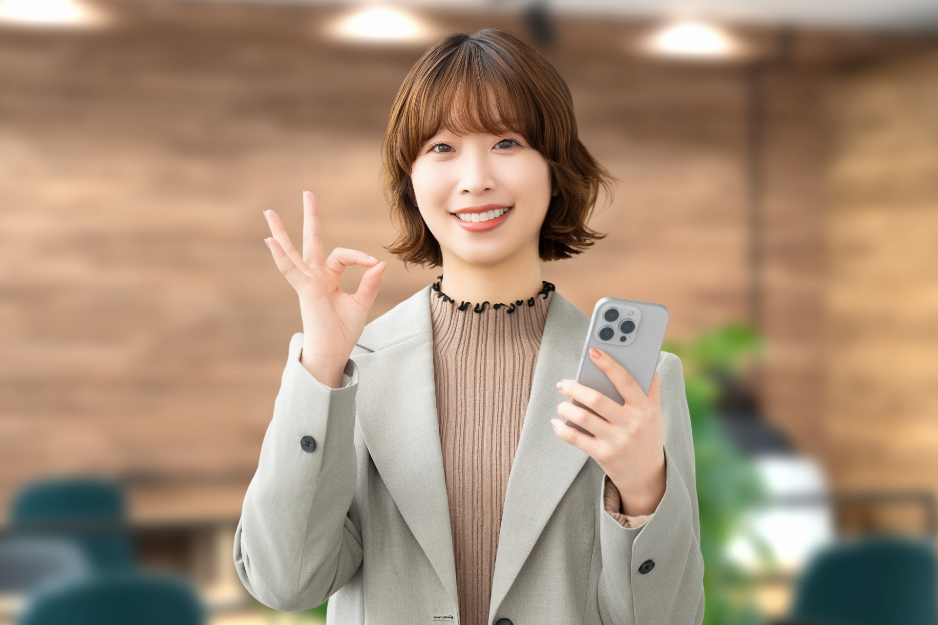 スマホを持ってOKポーズをする笑顔の女性