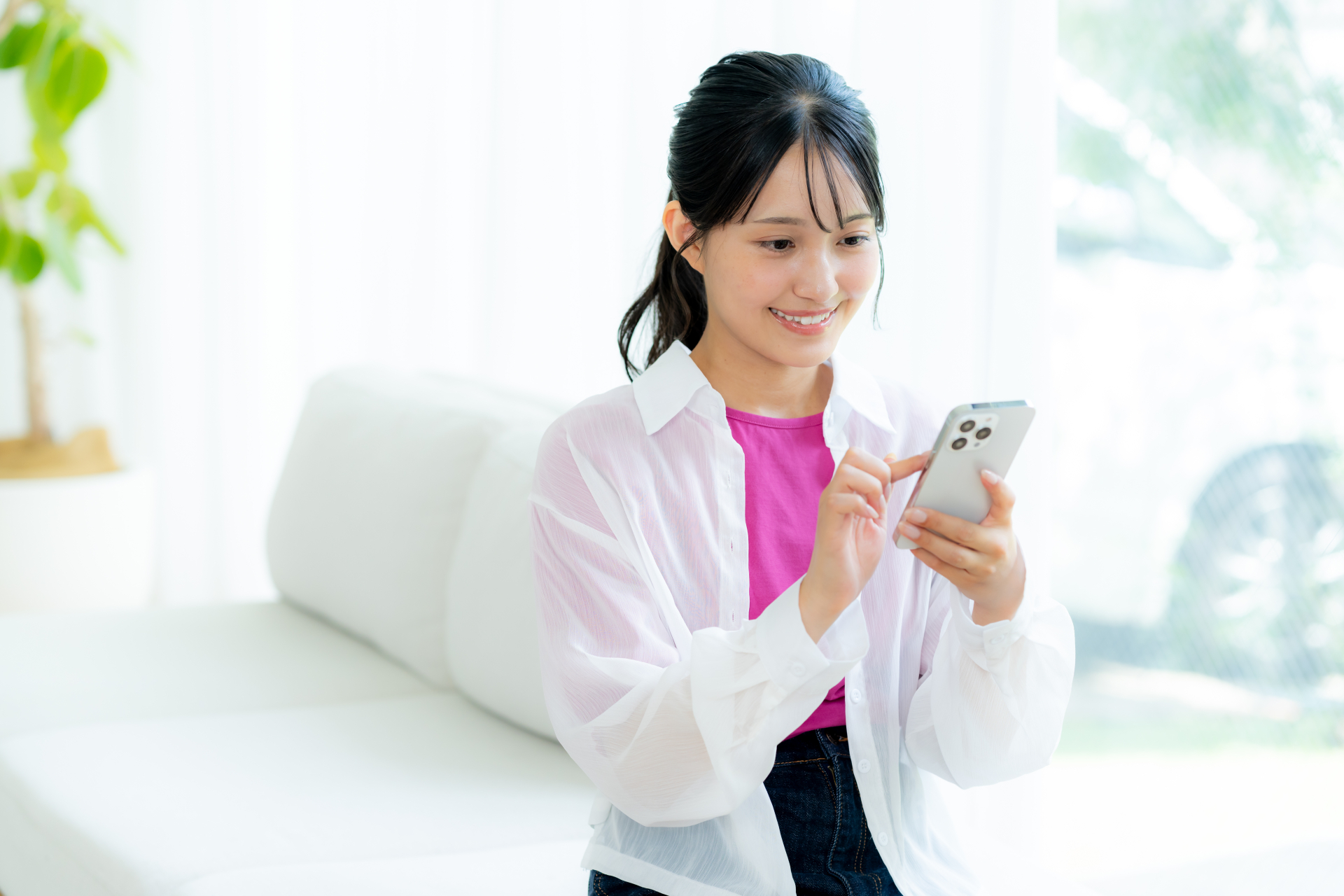 部屋でスマホを操作する若い女性