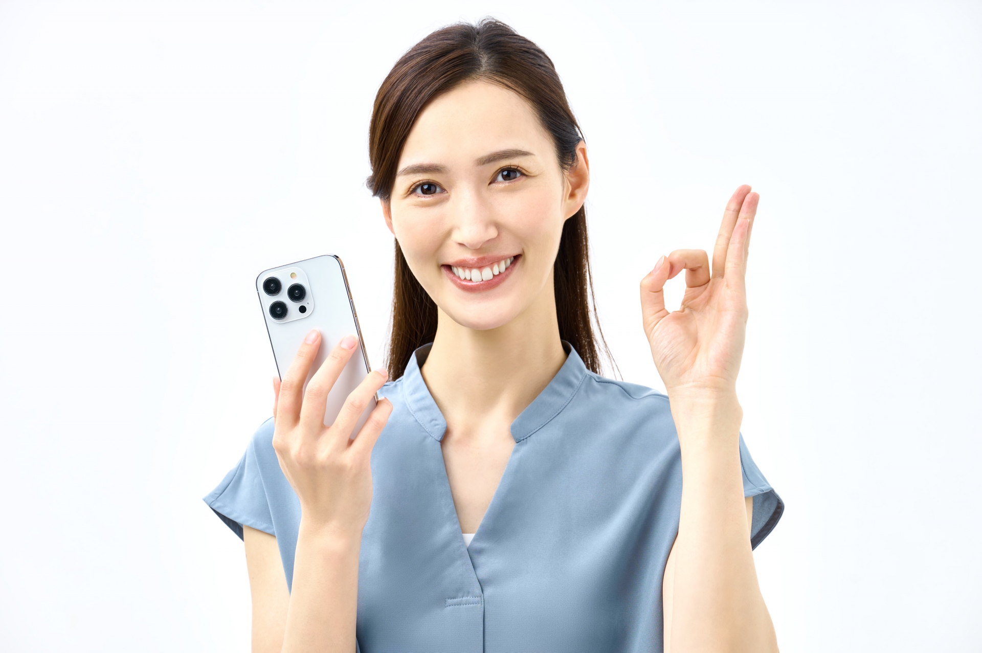 スマートフォンを持ちOKサインをする女性