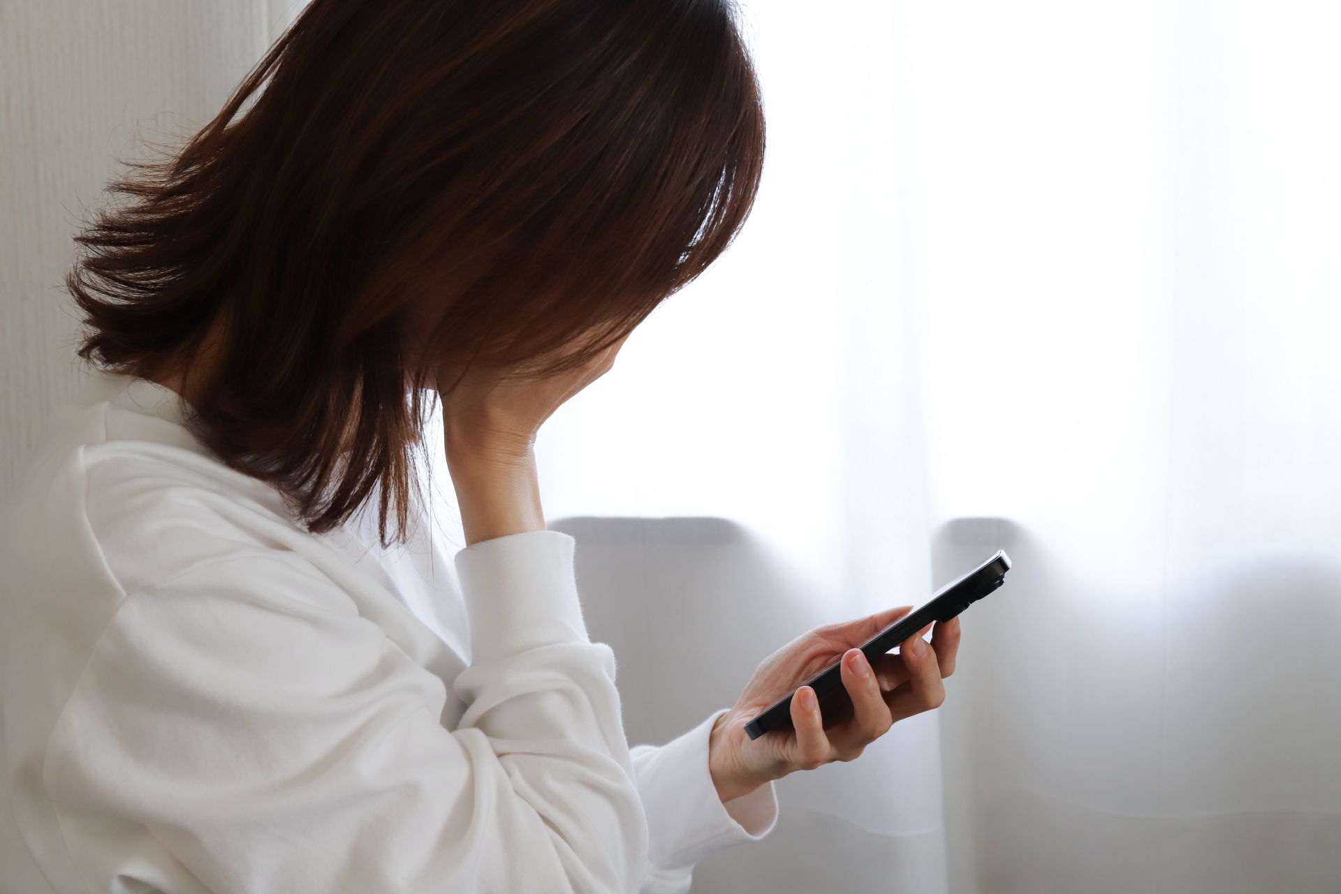 スマホを見て落ち込む女性