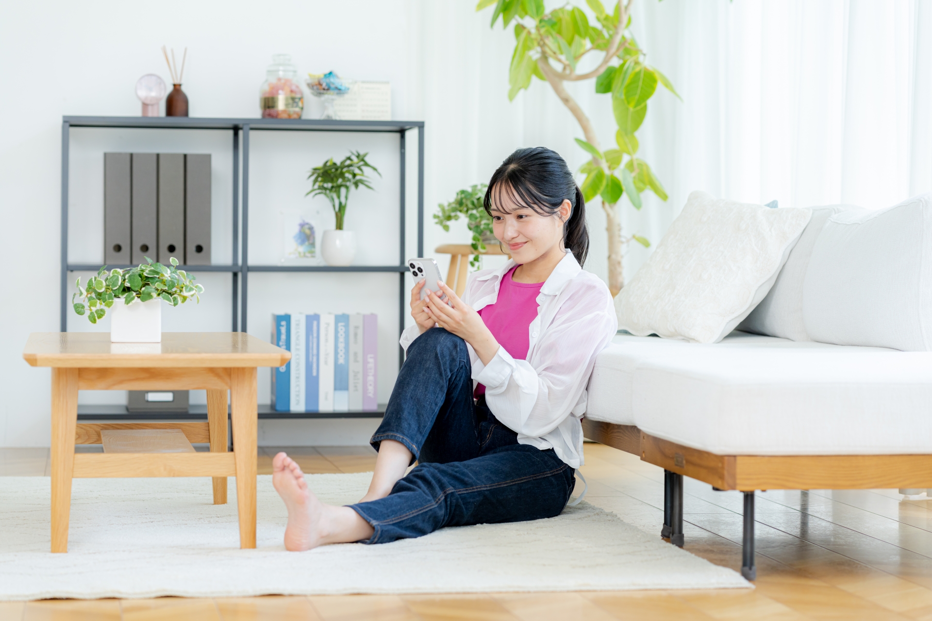 部屋でスマホを操作する若い女性