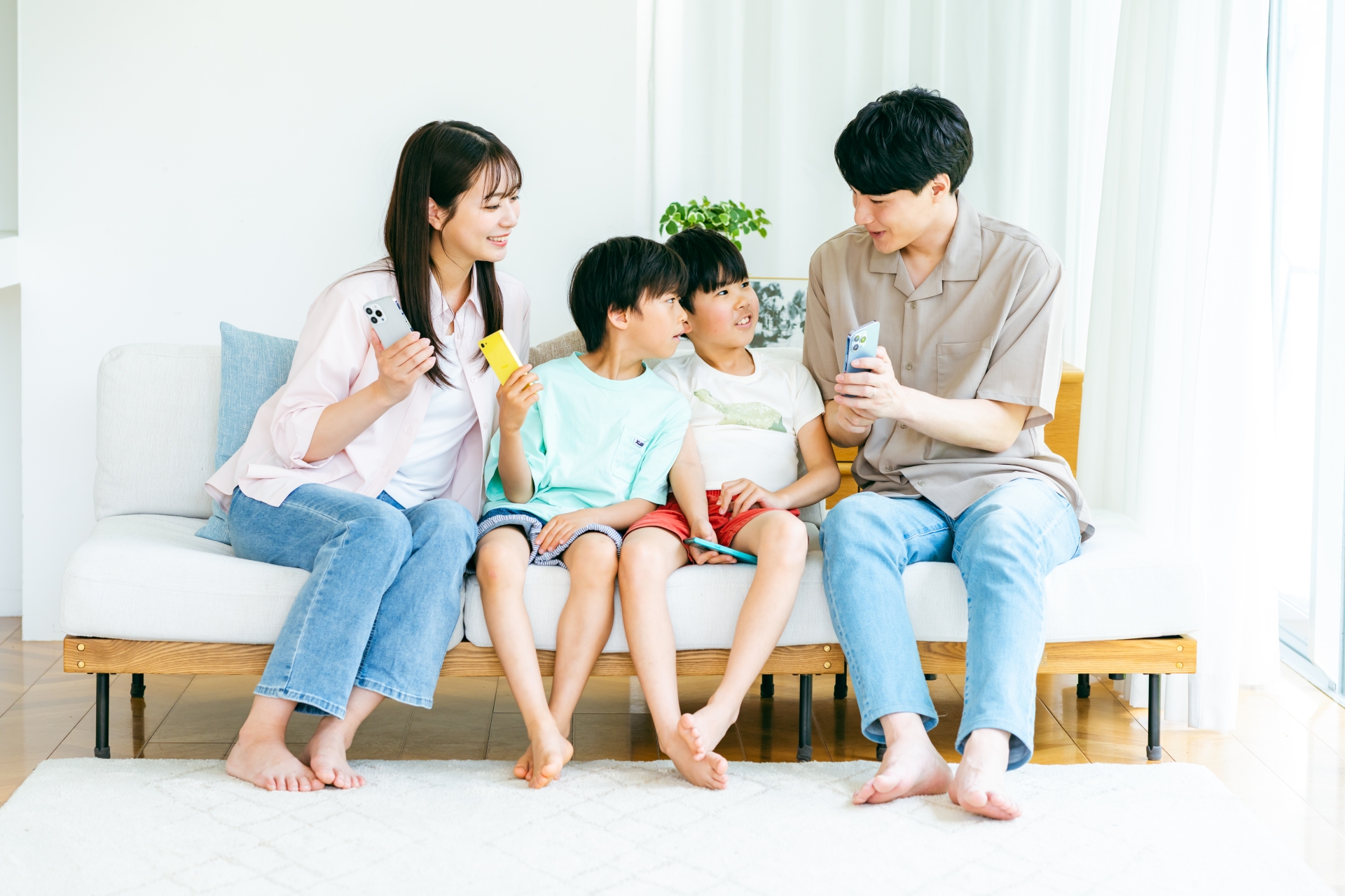 スマホを持ってソファに座る家族