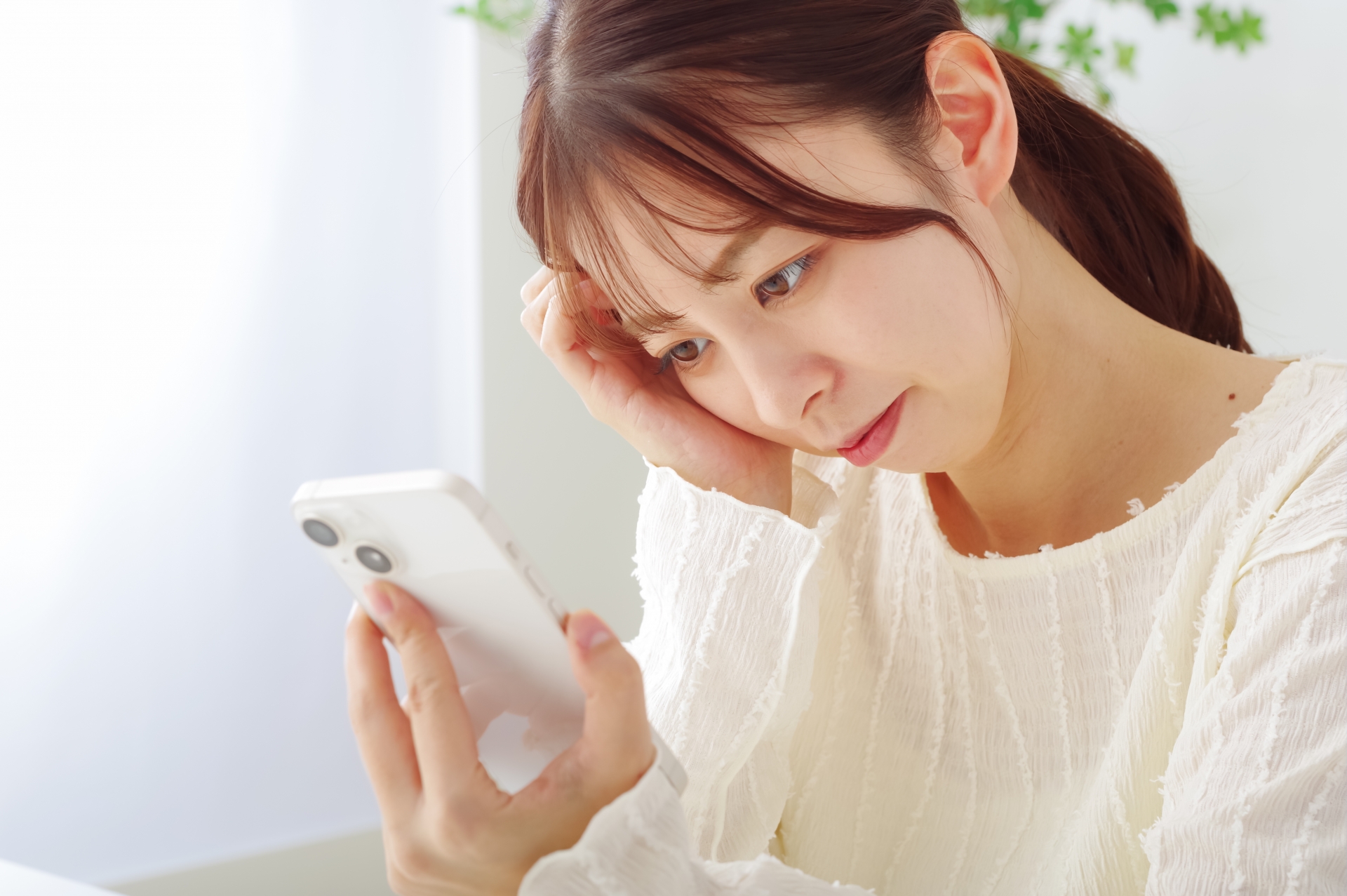 スマホを見て冴えない表情をする女性
