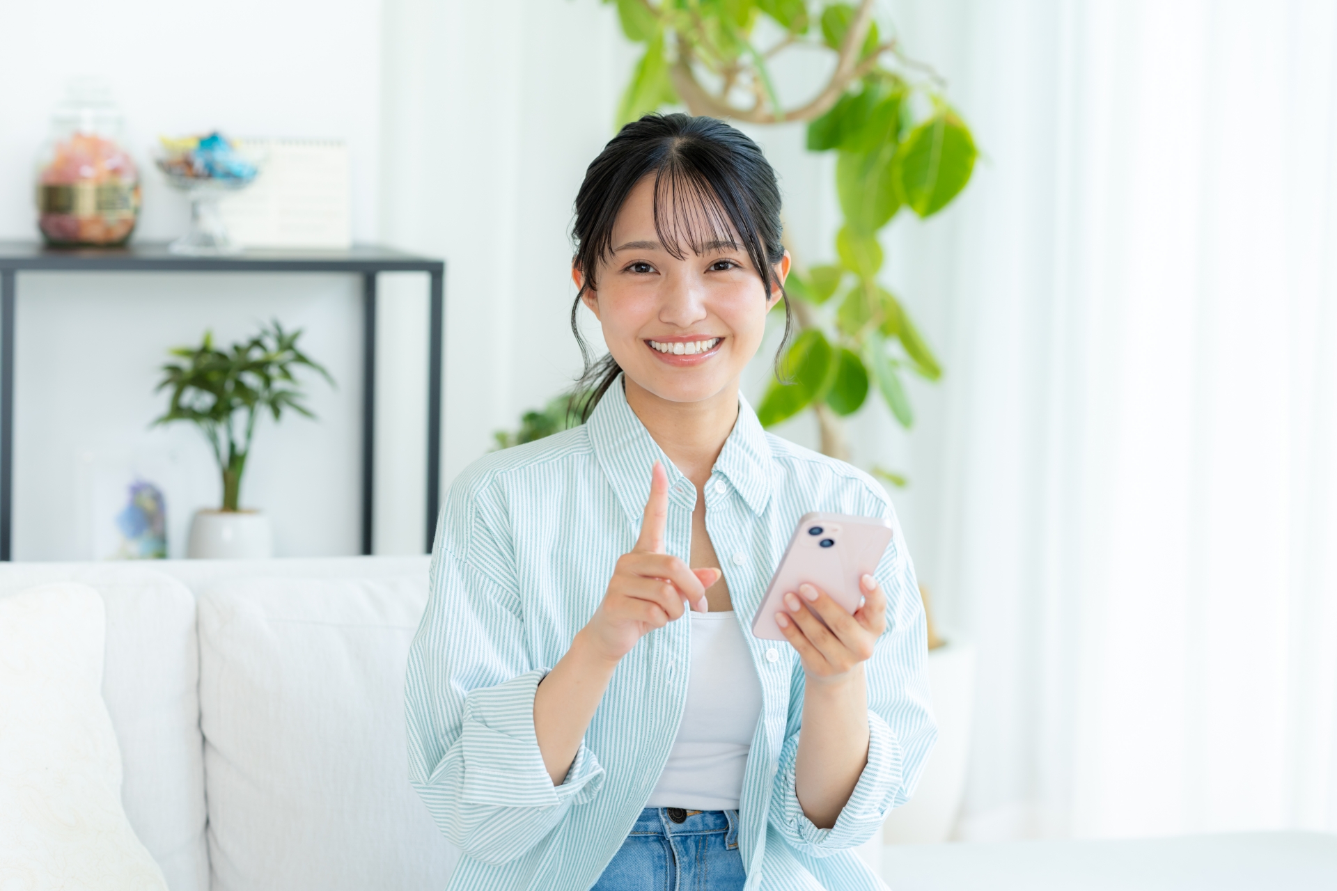 部屋でスマホを操作する女性