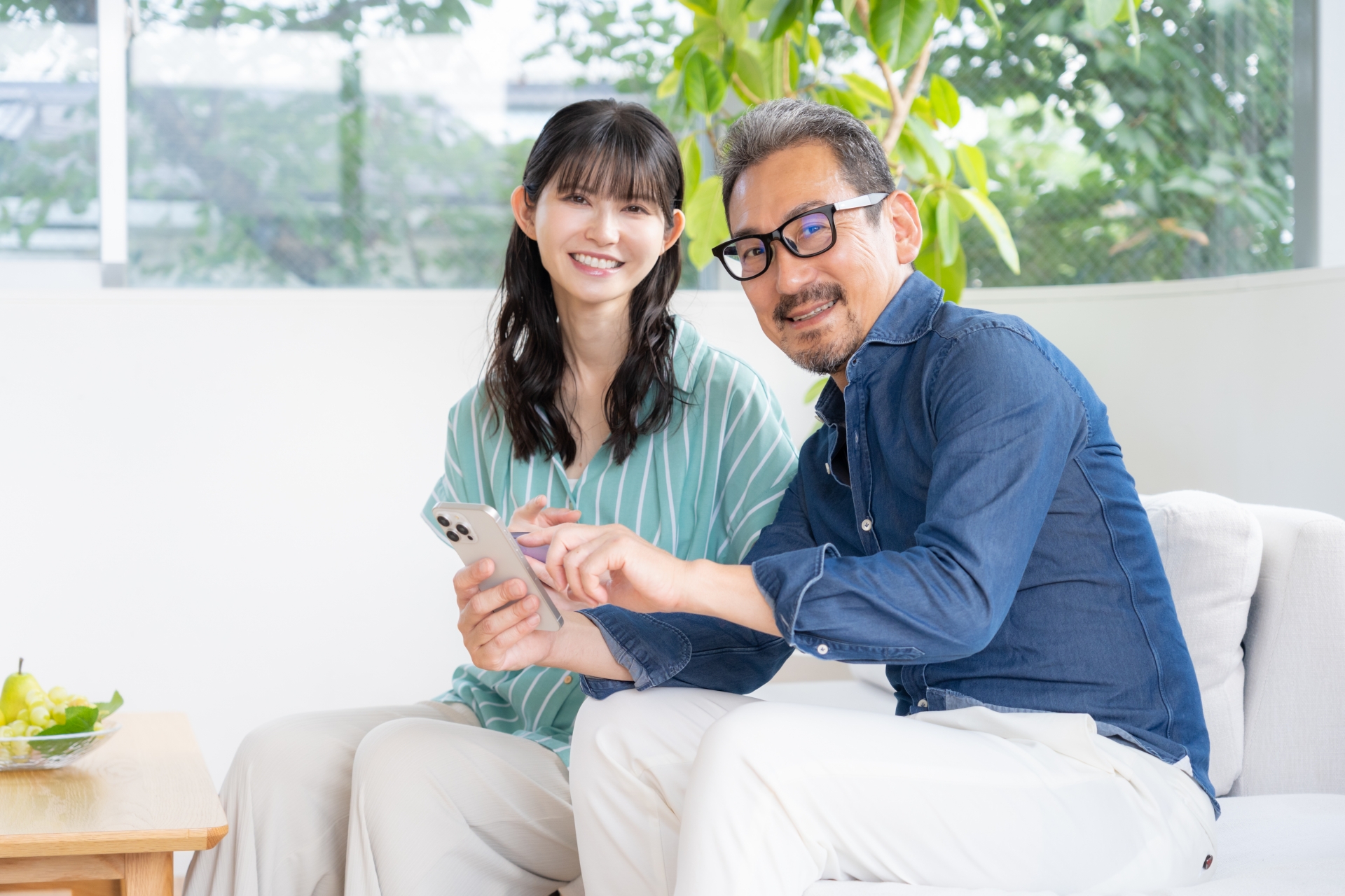 リビングでスマホを見るミドルの夫婦