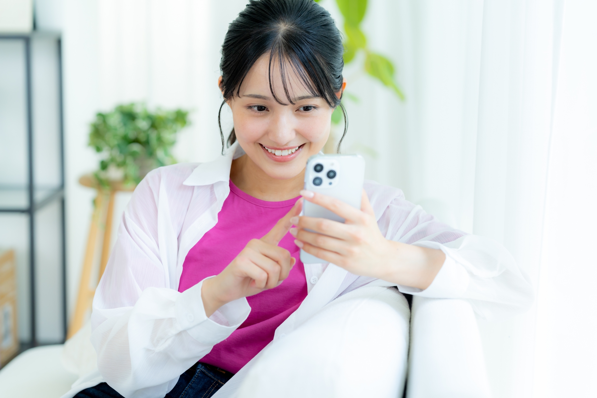 部屋でスマホを操作する若い女性