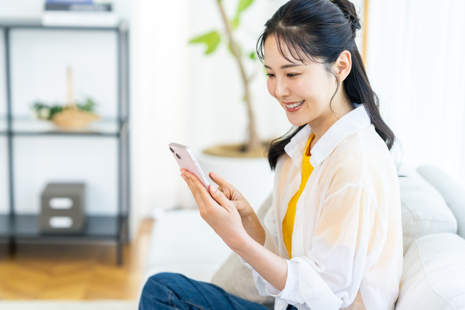 部屋でスマホを操作する女性