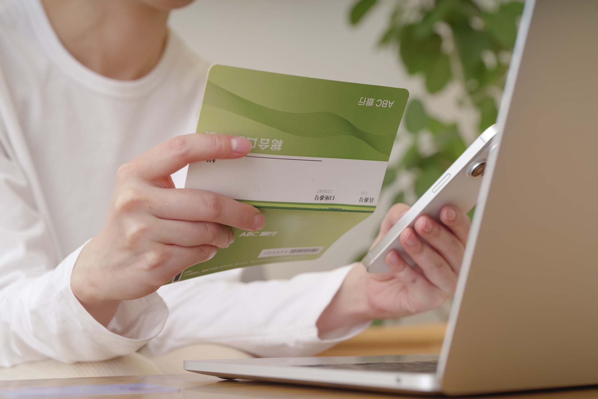 通帳とスマホを見る白いシャツの人