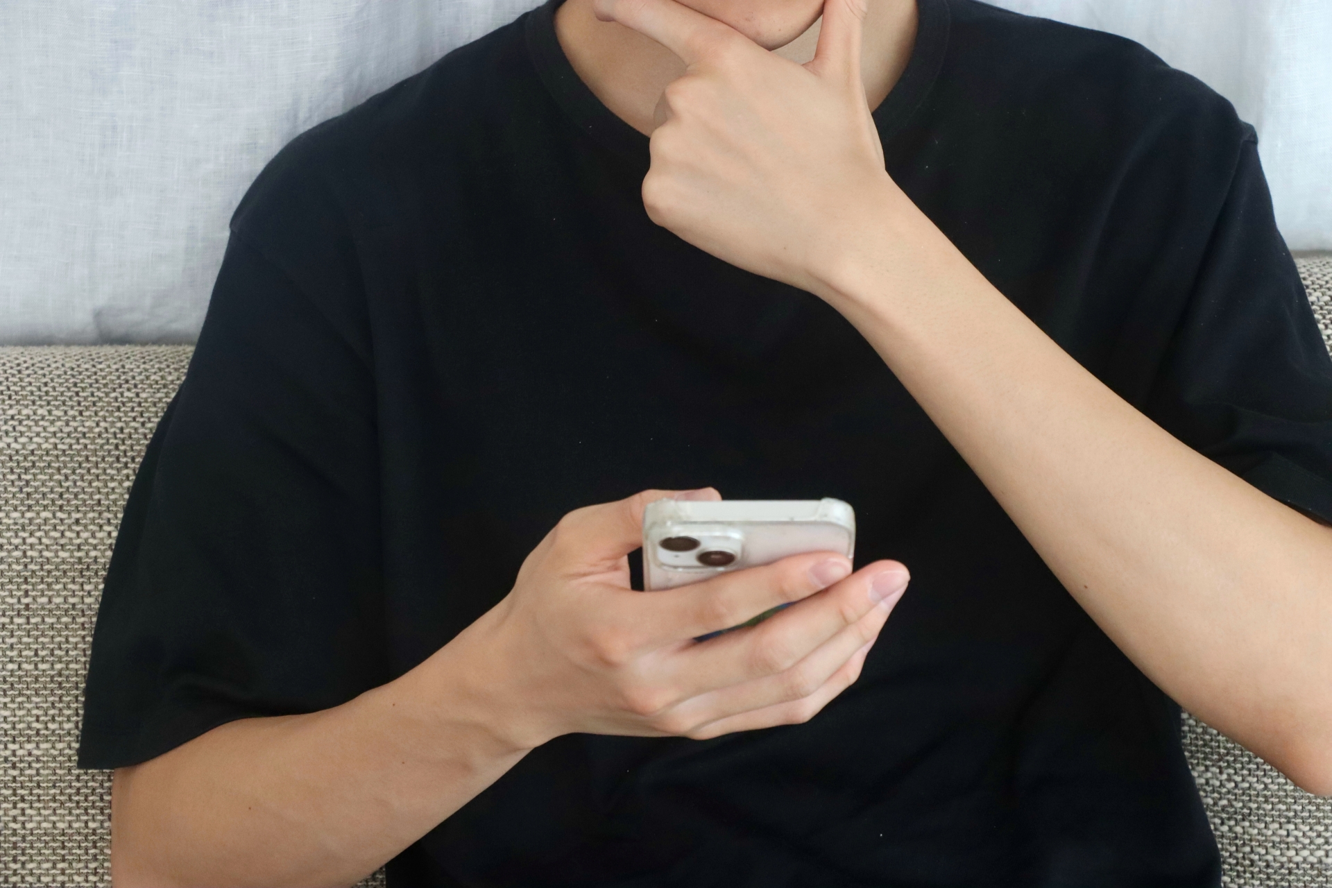 スマホを見ながら考える男性