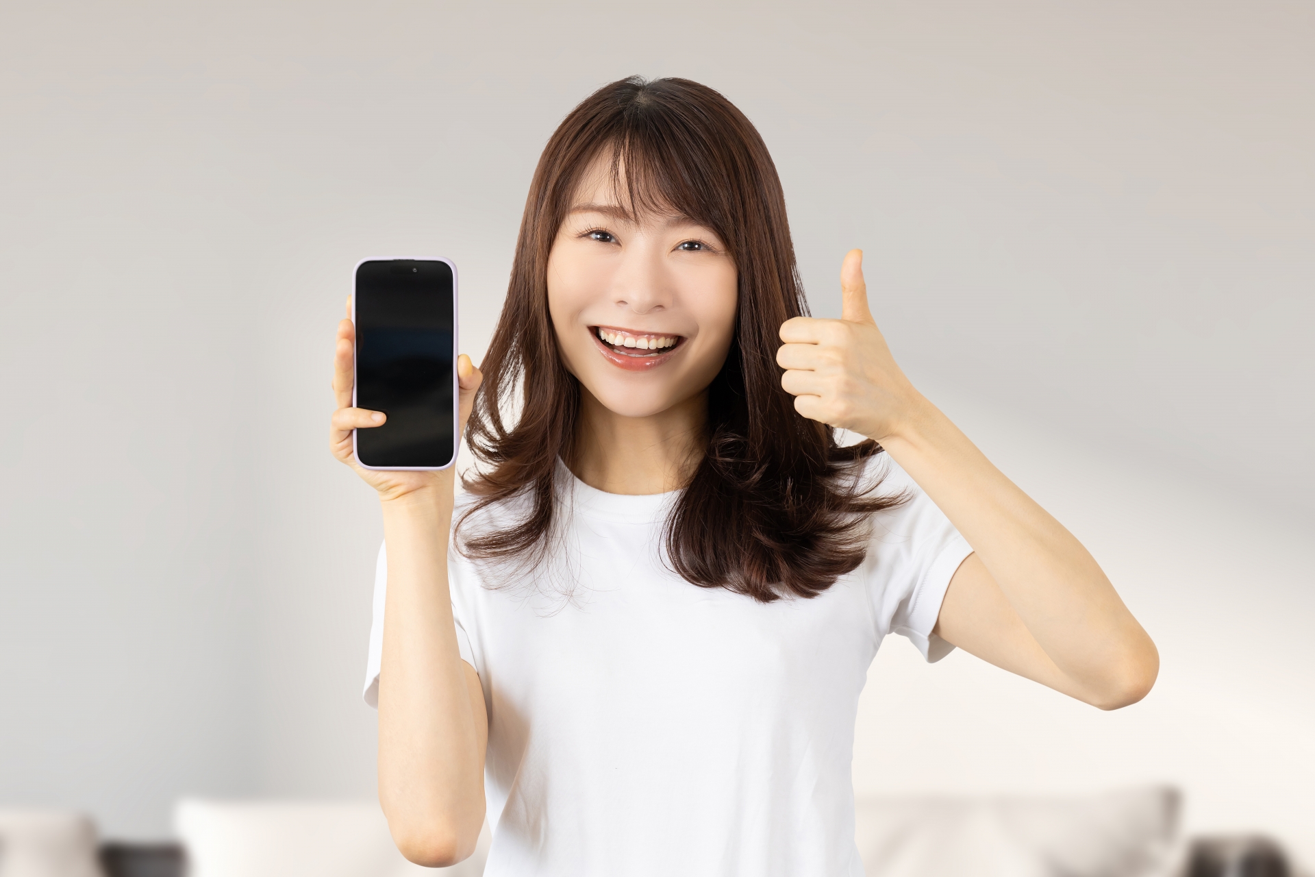 スマホを持っていいね！のポーズをする女性
